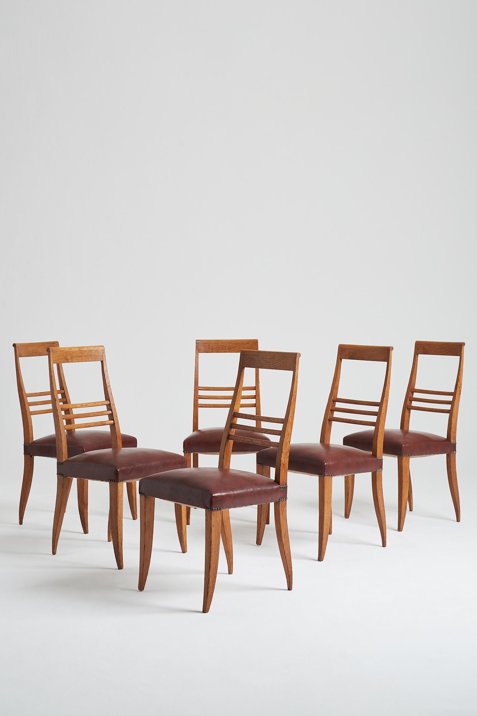 A set of six Art Deco oak dining chairs, with their original studded faux leather seat.
France, Circa 1935.