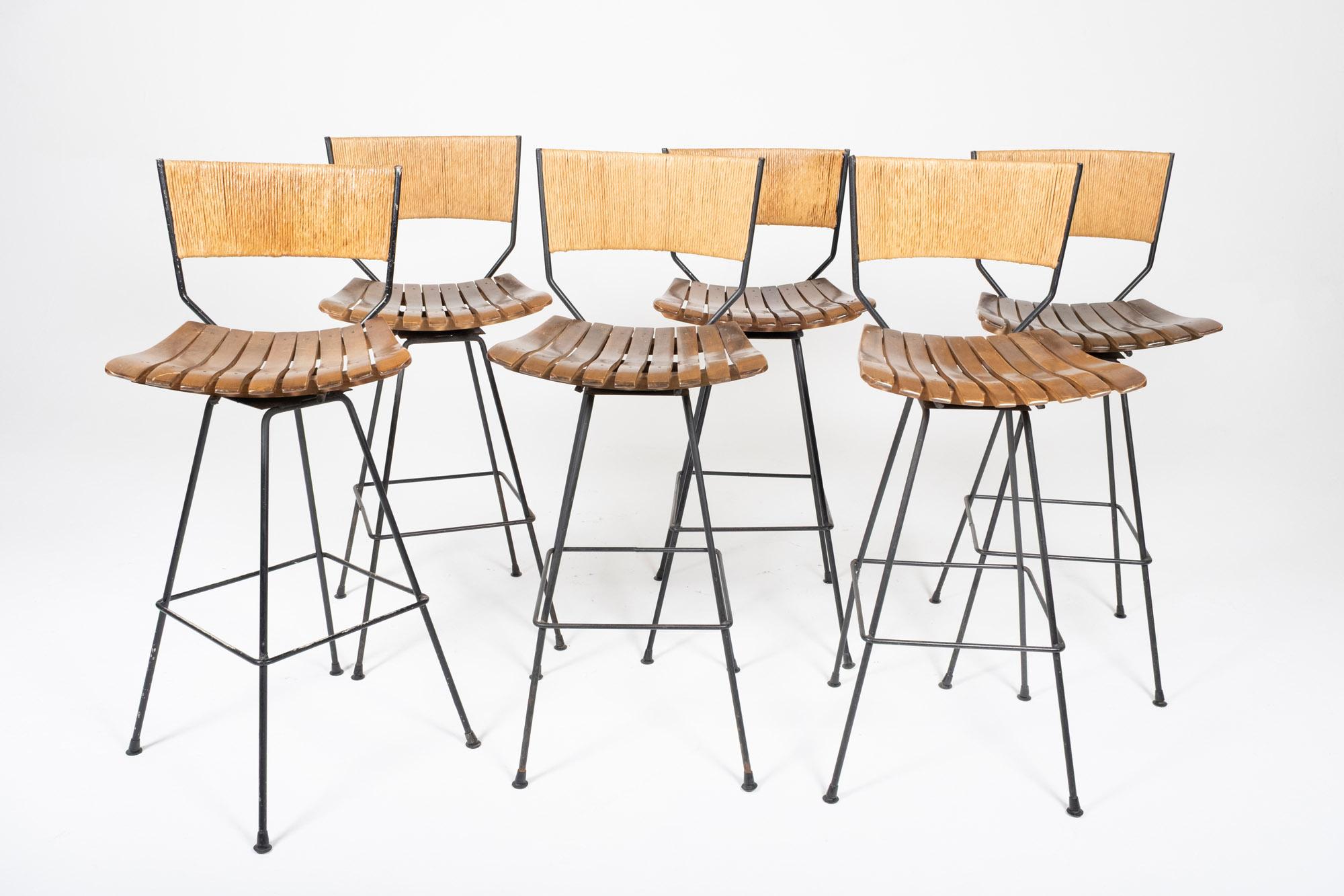 Mid-Century Modern Set of 6 Arthur Umanoff Swivel Seat Bar Stools in Slatted Wood, Raffia, & Iron For Sale