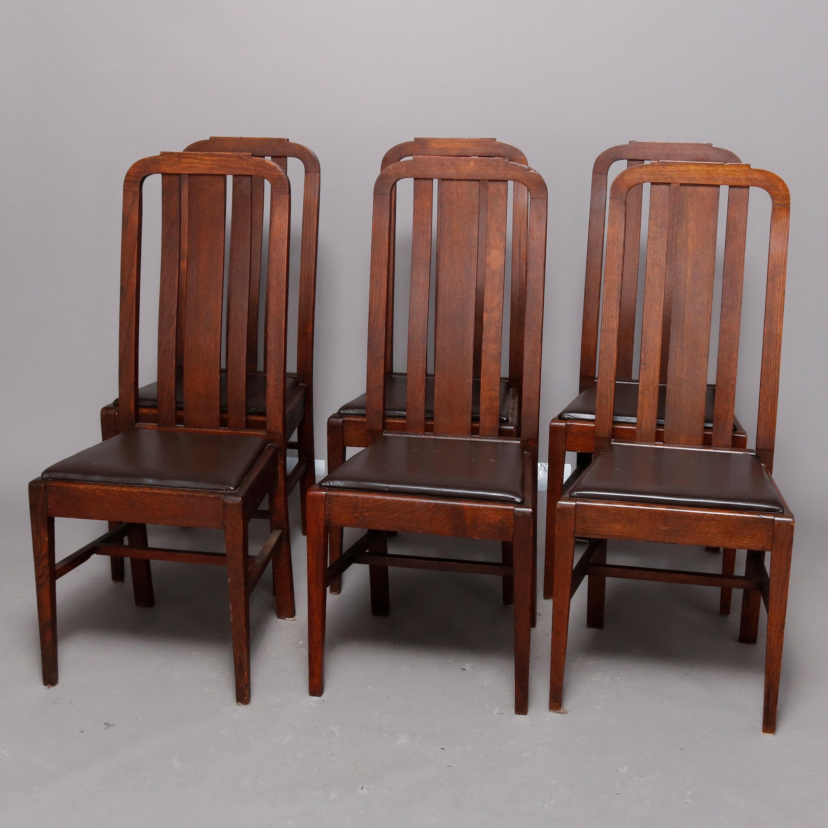 An antique set of Arts & Crafts mission oak dining room chairs by Greenwood Chair Co., Buffalo, New York offer tall and arched slat backs surmounting upholstered seats raised on straight and square legs, circa 1920

Measure: 41
