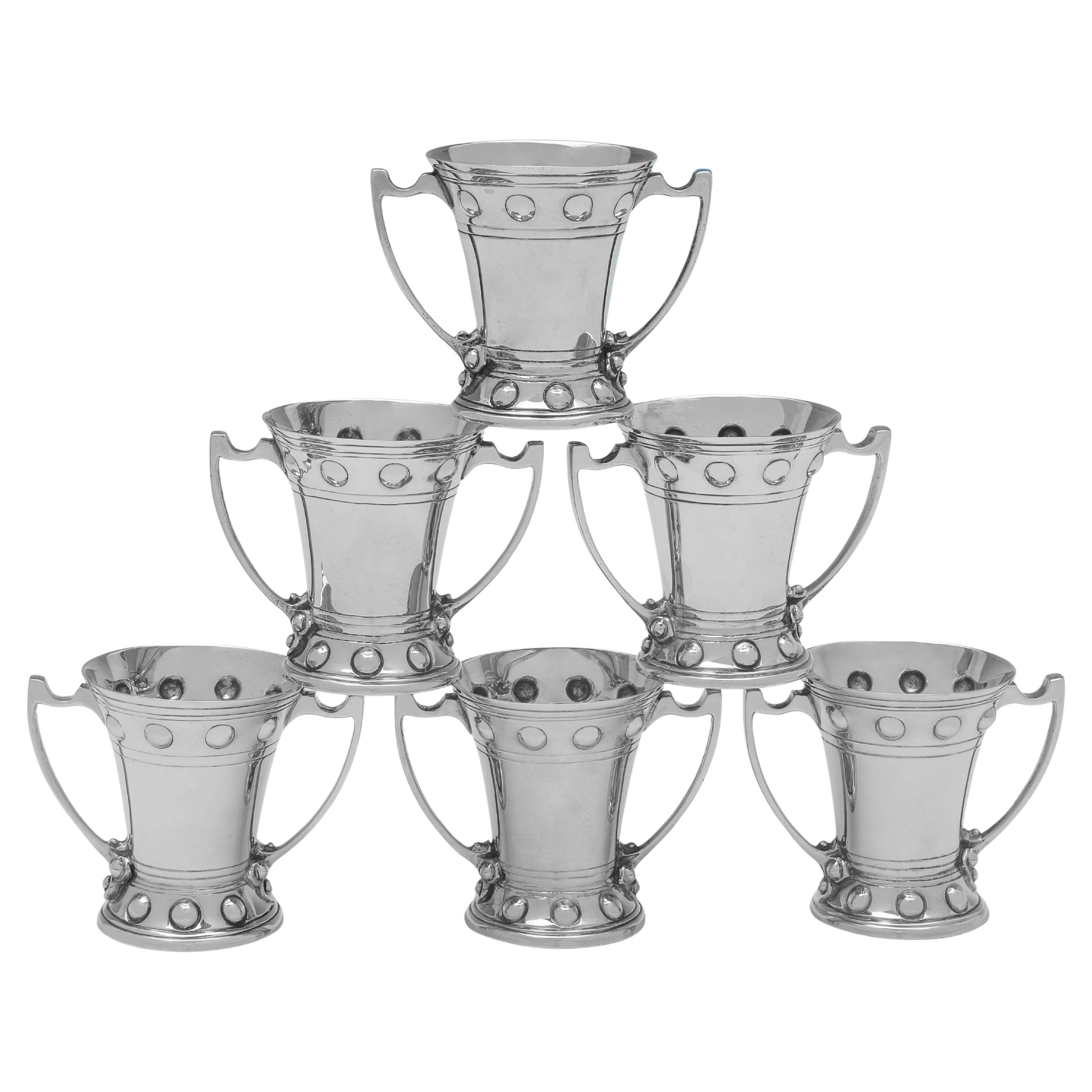 Poinçonné à Londres en 1905 par Goldsmiths & Silversmiths Co., cet élégant ensemble de 6 coupes en argent sterling anciennes de l'époque édouardienne est de style artisanal. Chaque tasse mesure 5 cm de haut, 6 cm d'une anse à l'autre et 4 cm de