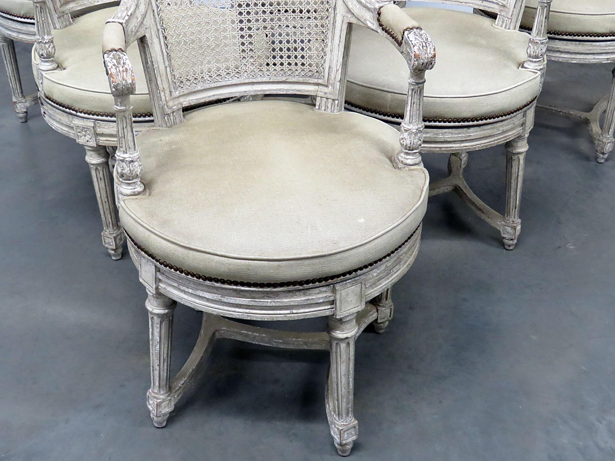 Set of 6 baker distressed finished swiveling dining room arm chairs with caned backs and nailhead trim. I 