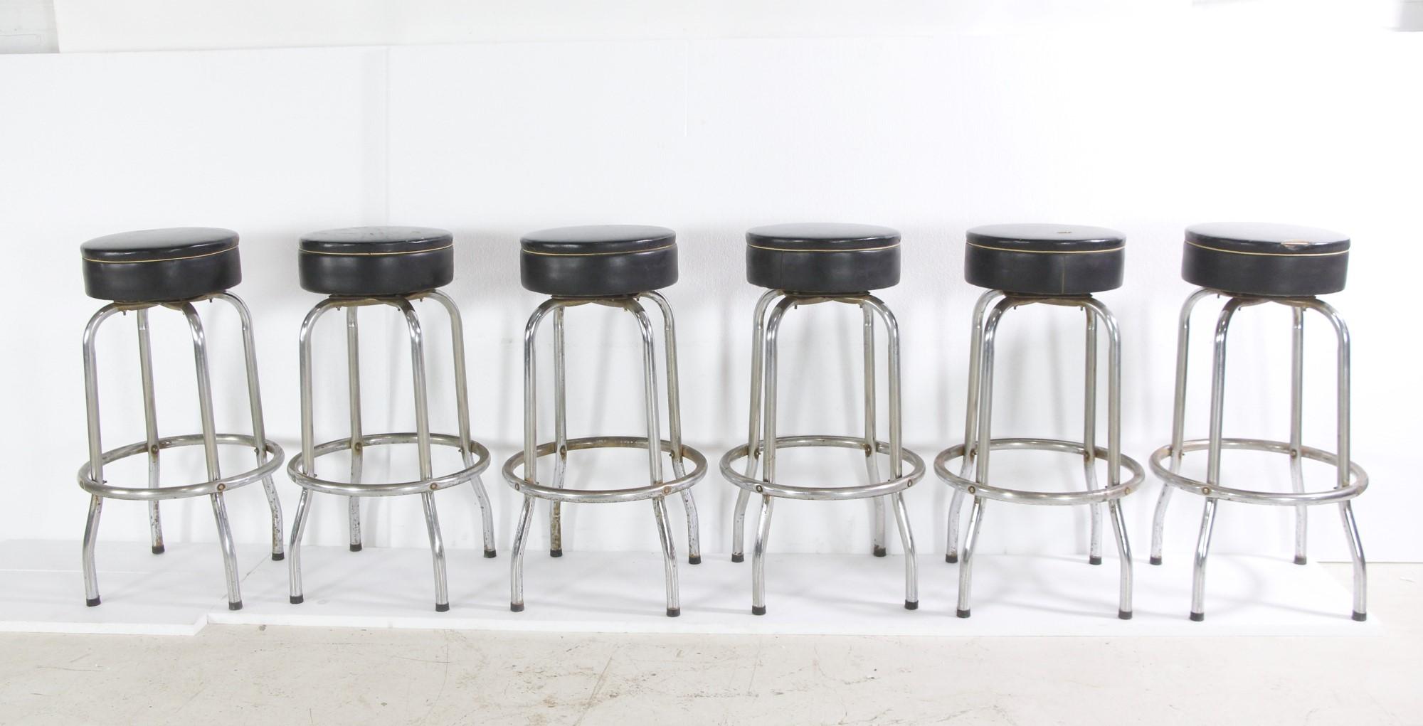Set of six last 20th century chrome plated bar stools. These feature round black vinyl cushioned seats. Rips, tears, and stains give these a vintage look. Please see photos. Priced as a set. Please note, this item is located in one of our NYC