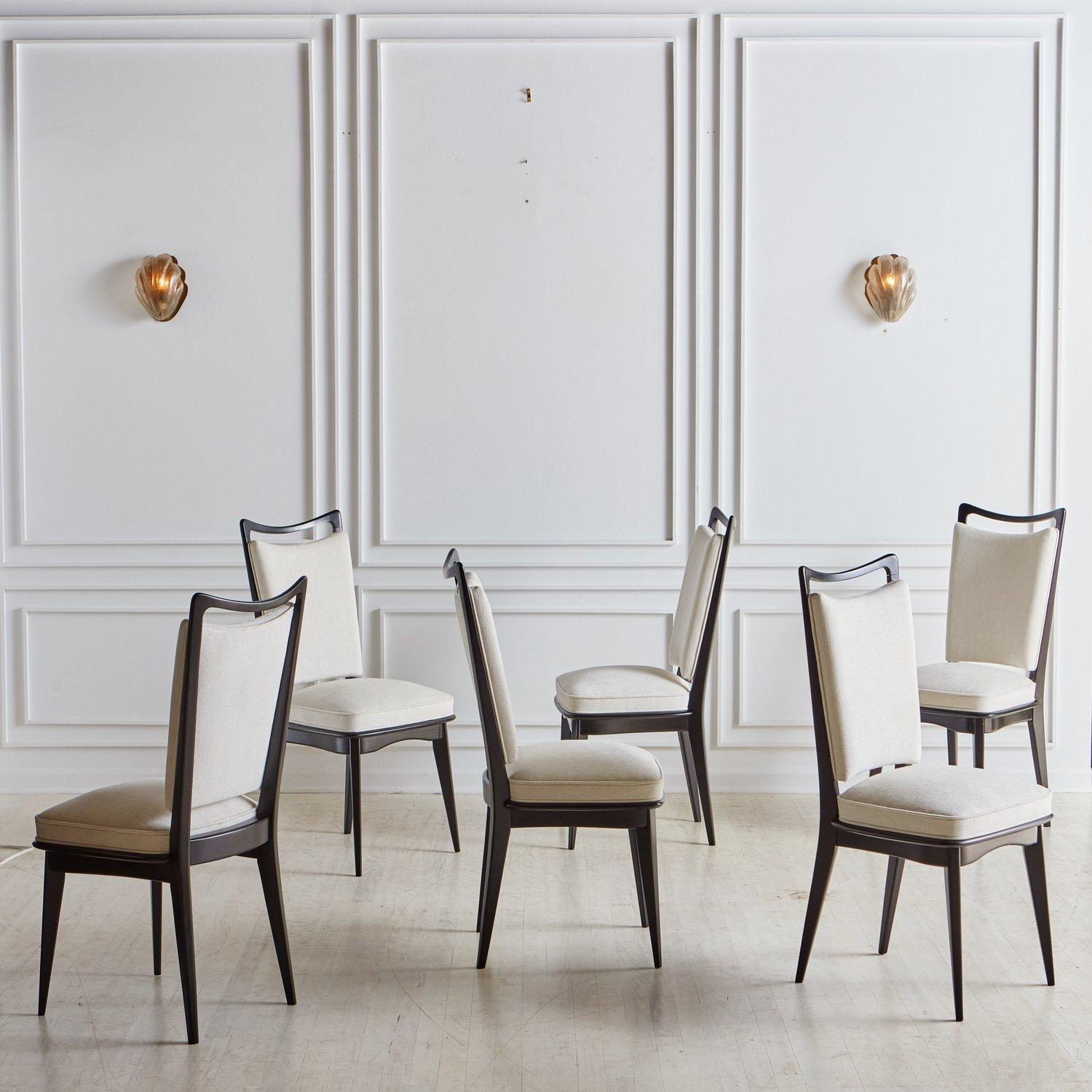 A set of 6 Italian dining chairs freshly reupholstered in a textured white fabric. These chairs have elegant black painted wood frames with subtly tapered legs. We love the classic shape and angular lines on these timeless dining chairs. Sourced in