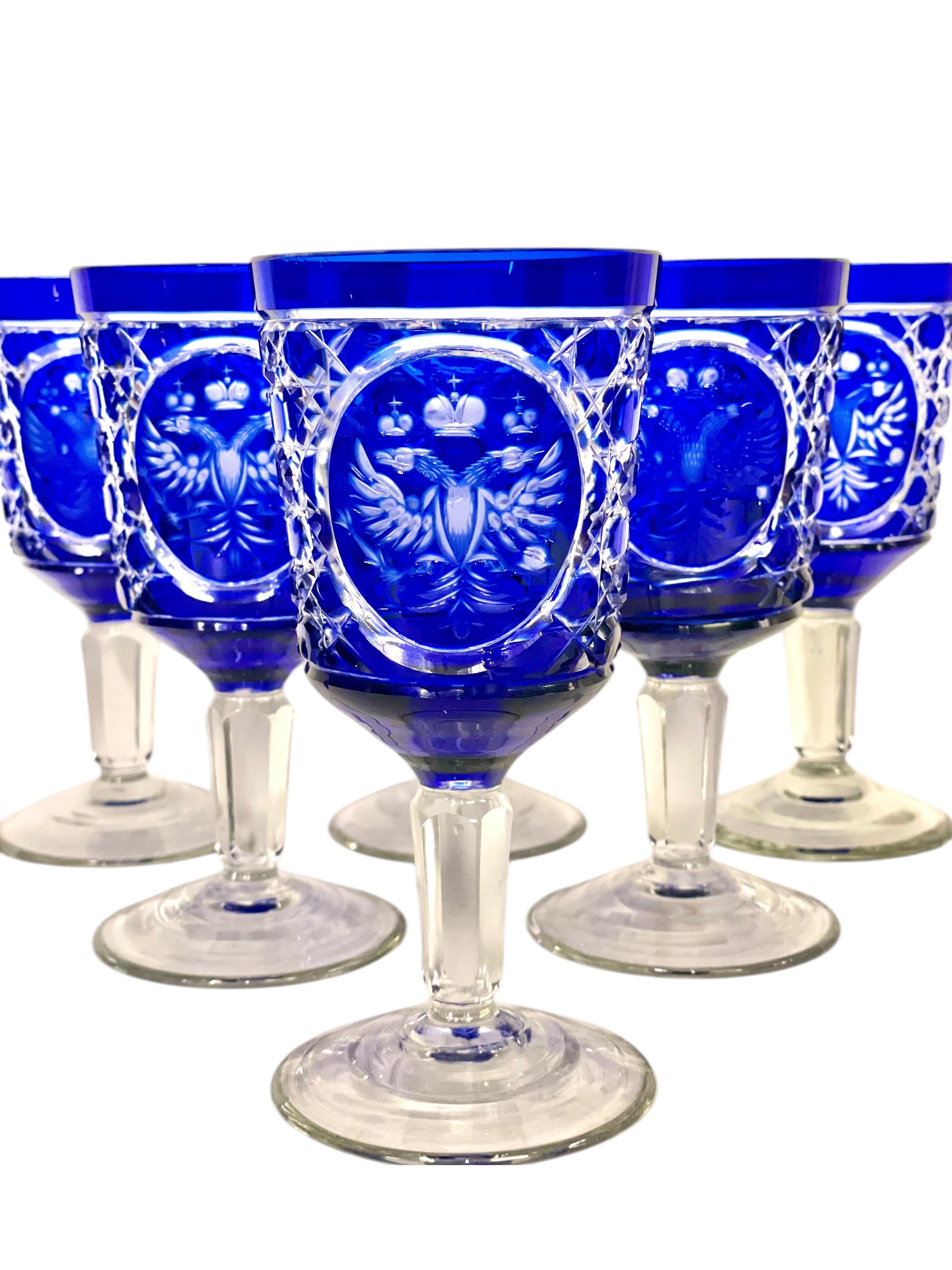 This exquisite set of six crystal goblets showcases the finest craftsmanship of Bohemian glassmaking. Each piece is meticulously crafted in deep cobalt blue overlay crystal, intricately cut through to clear crystal to reveal a remarkable etched