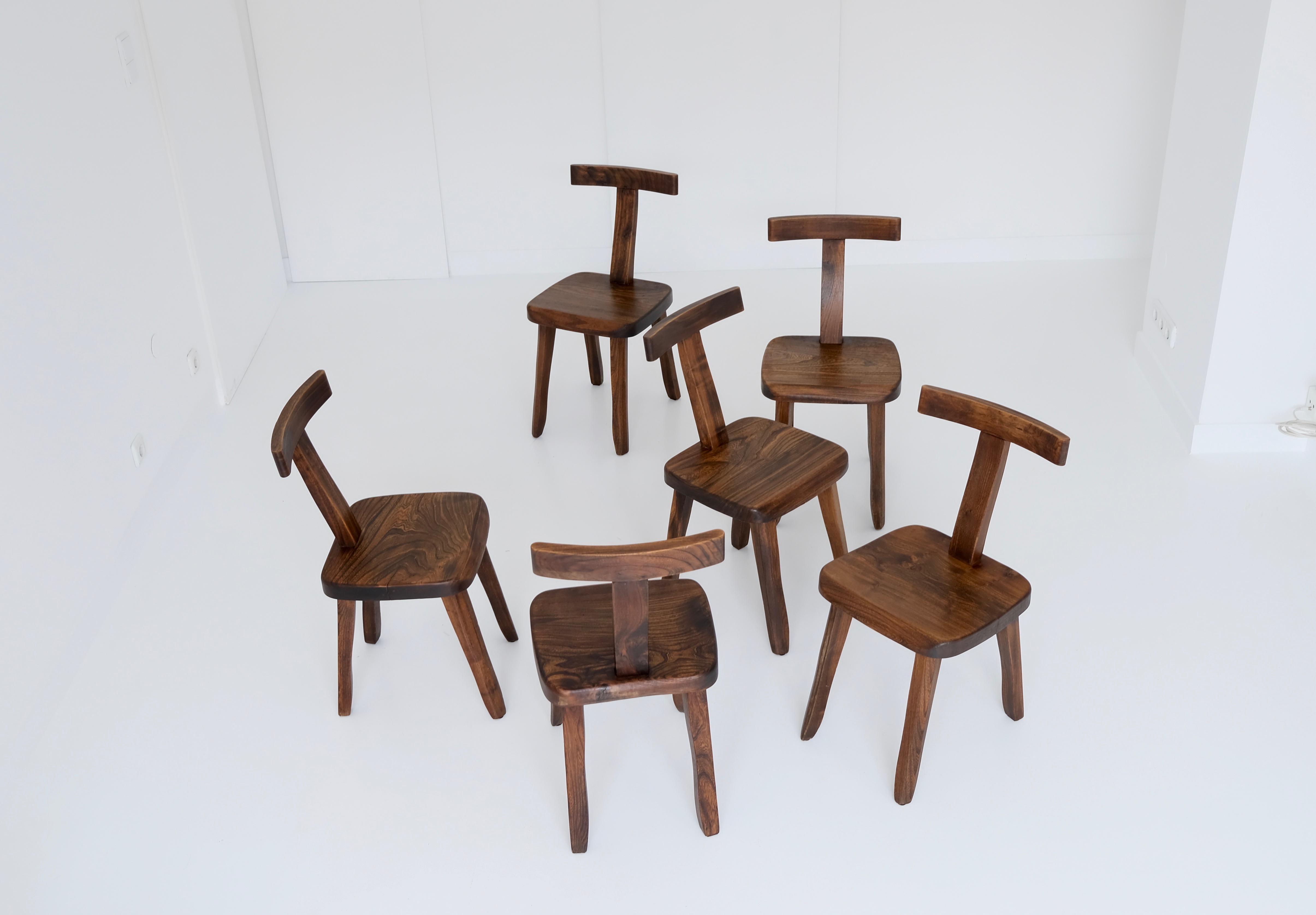 The solid chairs are made of stained elm wood and sculpturally crafted by hand. Rustic, minimalistic, brutalistic – bringing a sense of organic power to every understated design interior.