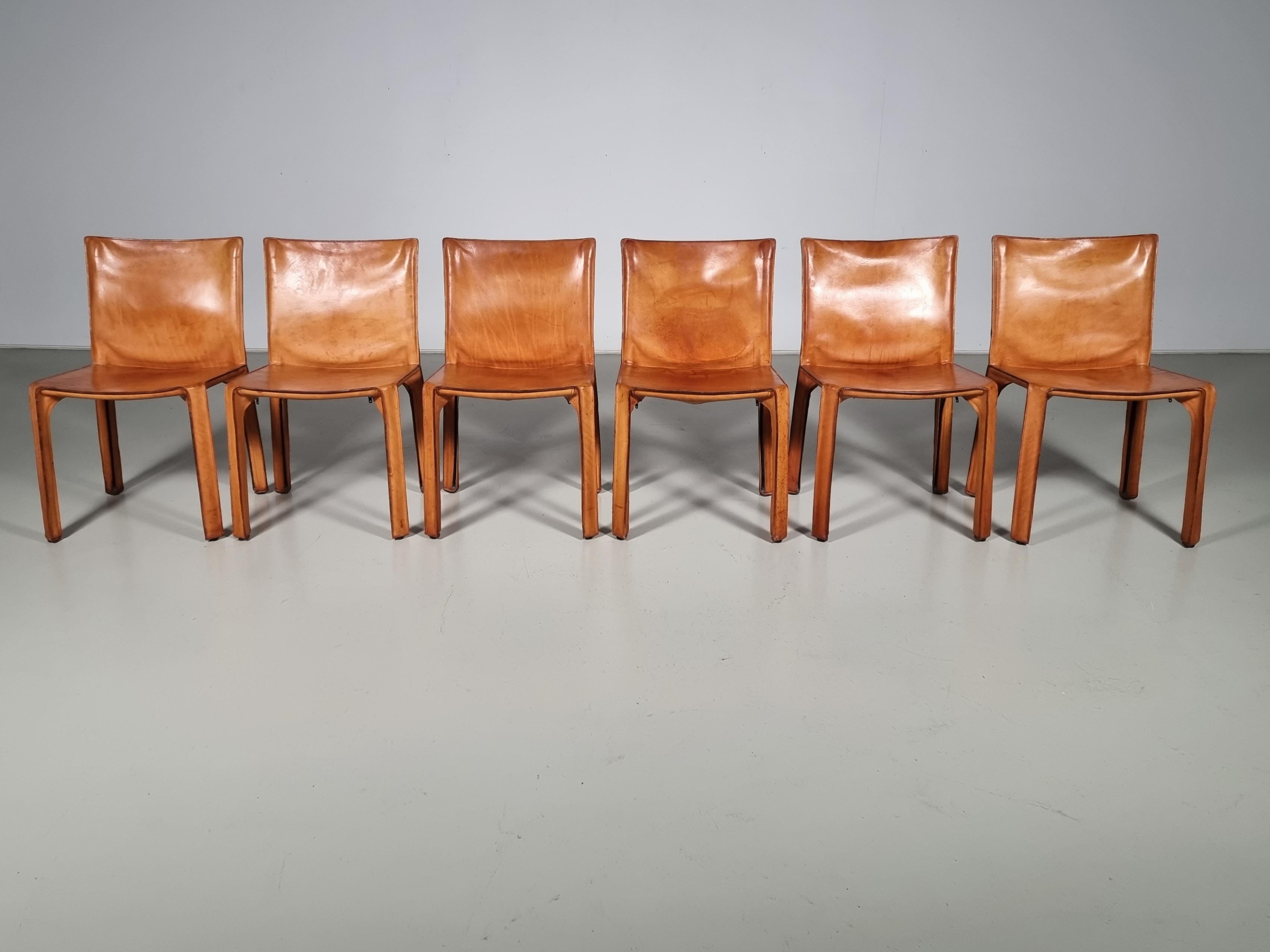 Set of 6 early edition CAB-412 dining room chairs in cognac saddle leather. Designed by Mario Bellini and manufactured by Cassina in the 1970s in Italy. The leather cover is stretched over a minimal tubular steel frame. The only additional