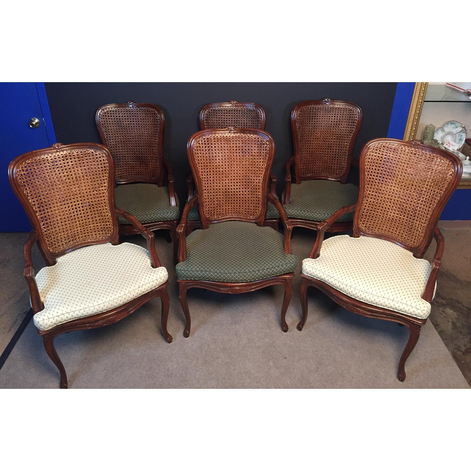 Set of 6 Carved Wood and Caned Dining Arm Chairs. Six dining chairs with double caned backs and upholstered seats. Two with white print seats and 4 with green print seats. Hand caning on front and rear of back as well as seat. Carved floral design