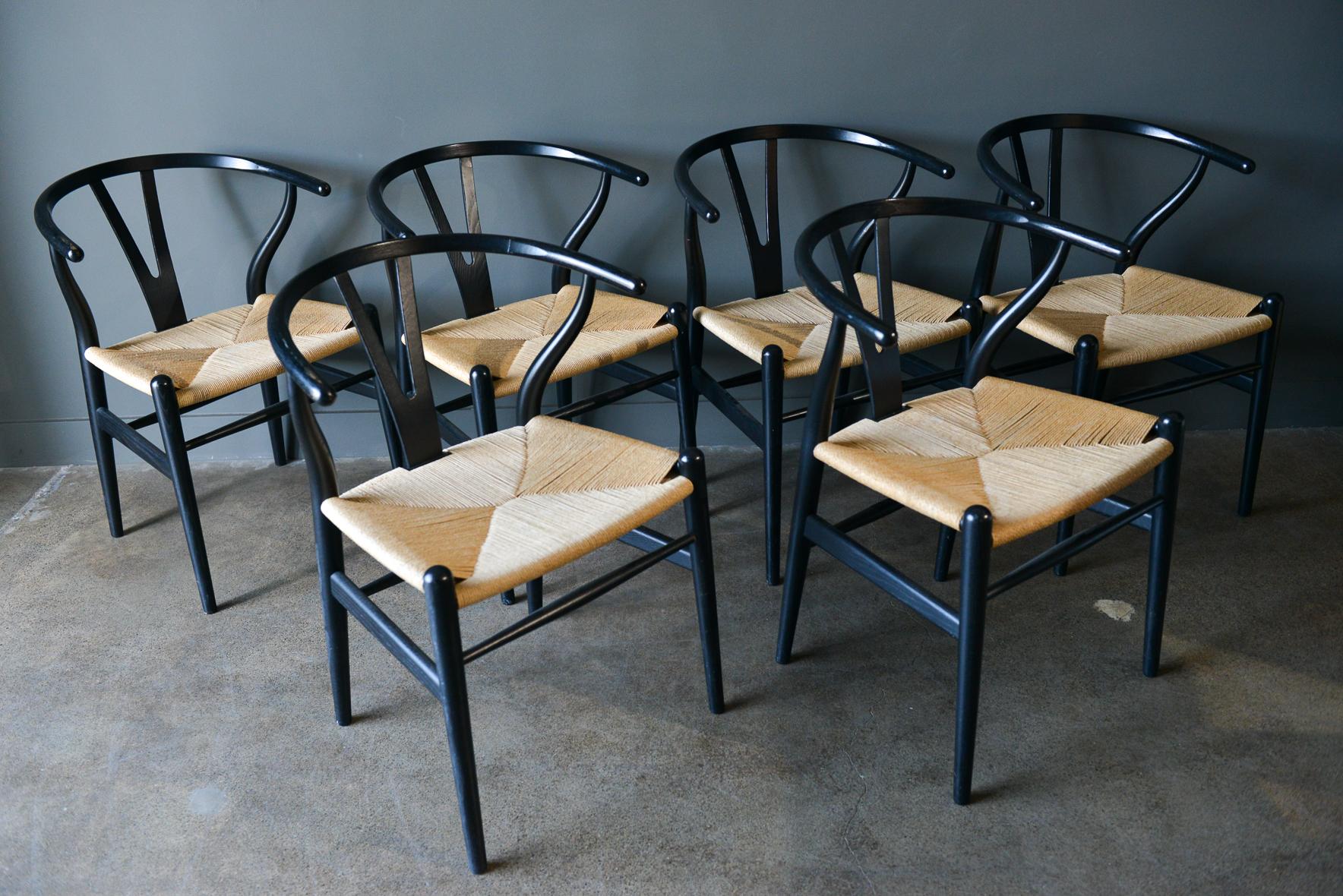 Set of 6 CH-24 Wishbone chairs by Hans Wegner in ebonized oak. Signed on underside, these are in very good original condition with only slight wear on some armrests as shown. Papercord seats are original and intact, see photos. Beautiful set of 6