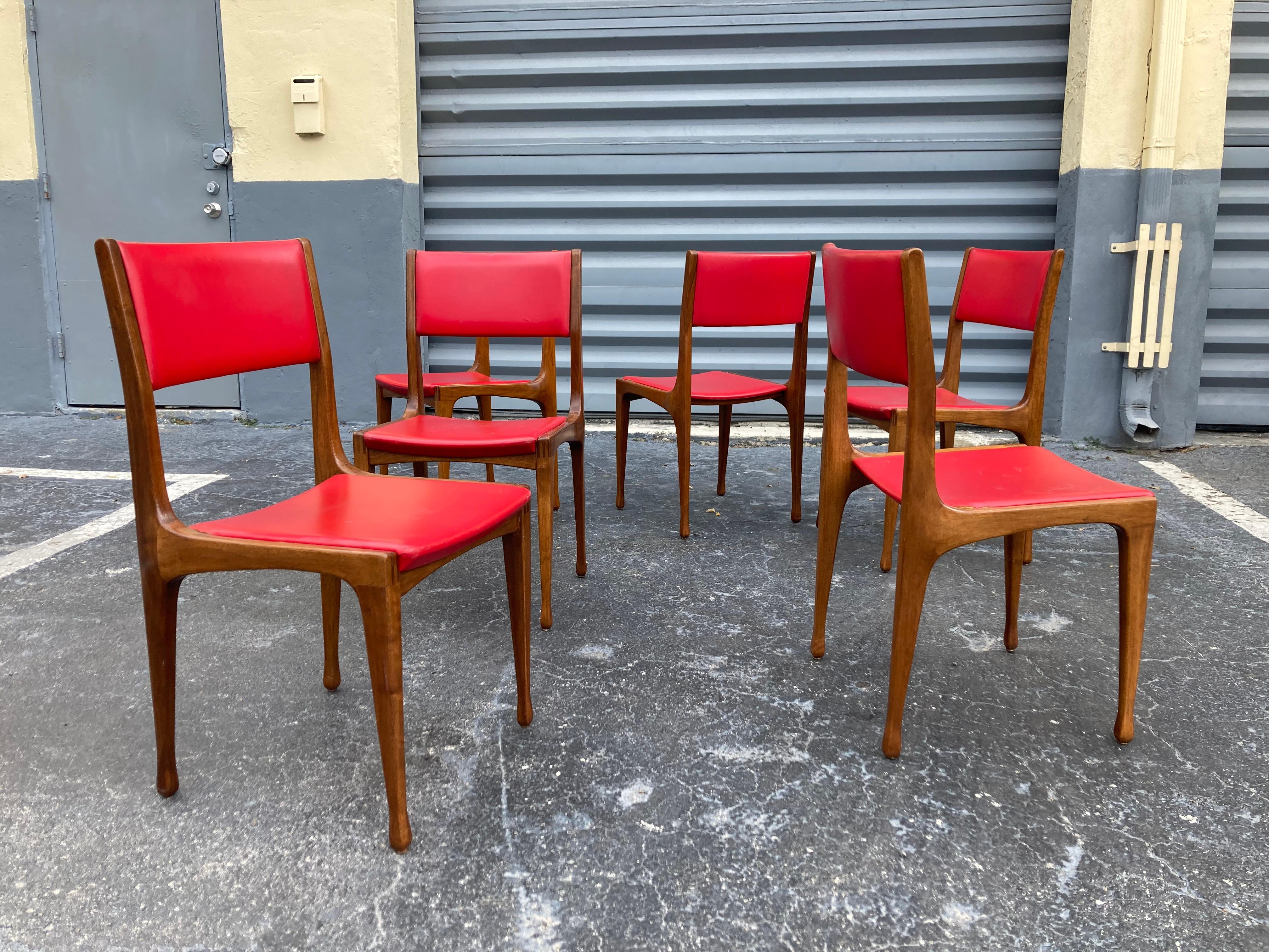 Set of 6 chairs Mod. 693, Designed by Carlo de Carli for Cassina.
All original condition. Solid walnut and red vinyl. 
 We can help if buyer wants seats and backs recovered.