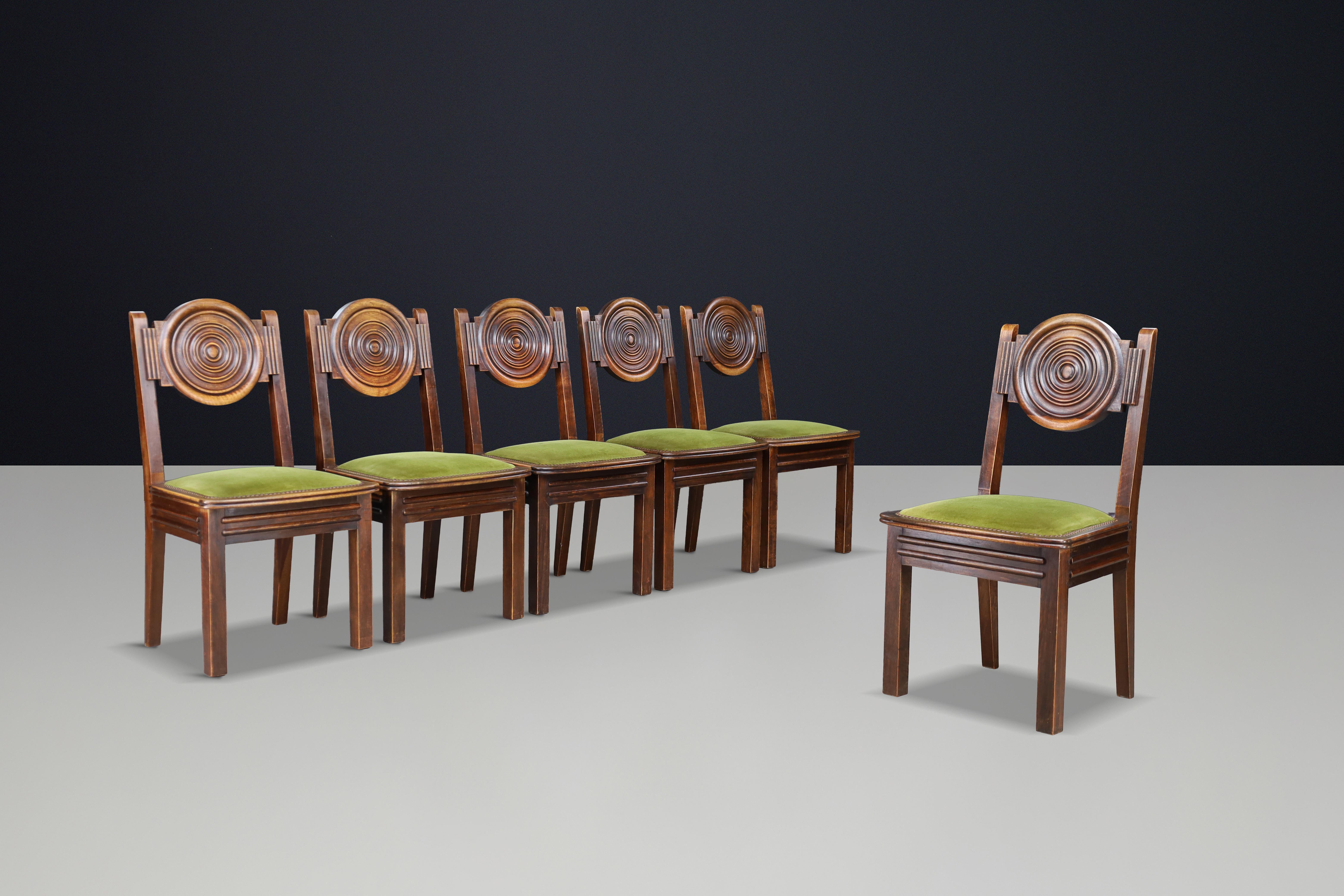 Magnifique ensemble de six chaises de salle à manger en chêne sculpté par Charles Dudouyt, avec des dossiers circulaires sculpturaux, des cadres en chêne patiné et un revêtement en velours vert d'origine.

Cet ensemble exceptionnel de six chaises de