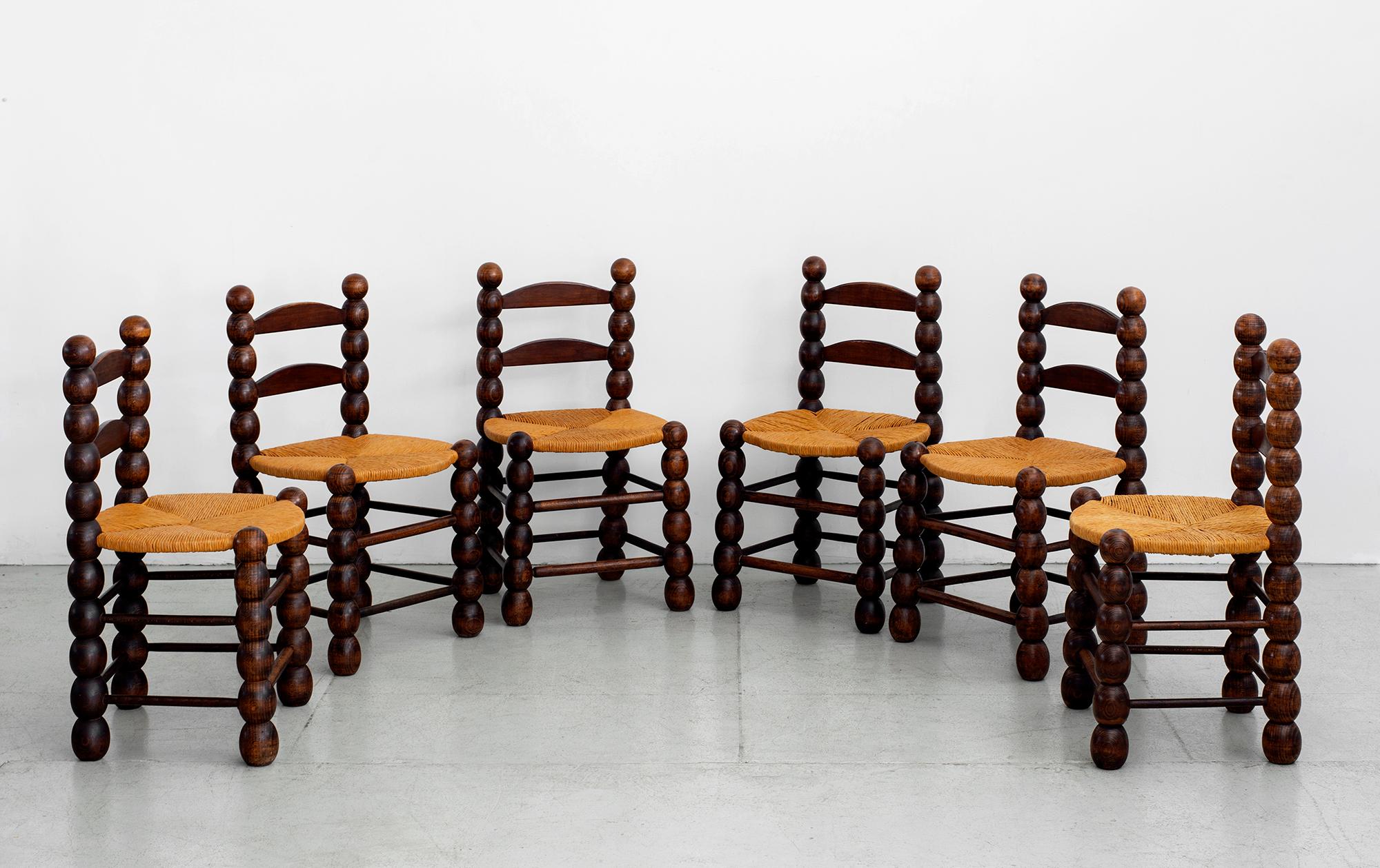 Rare set of 6 French dining chairs by Charles Dudouyt. 
Gorgeous patina'd oak frames with signature sculptural ball shapes. 
Woven rushed seats. 
Fantastic set.