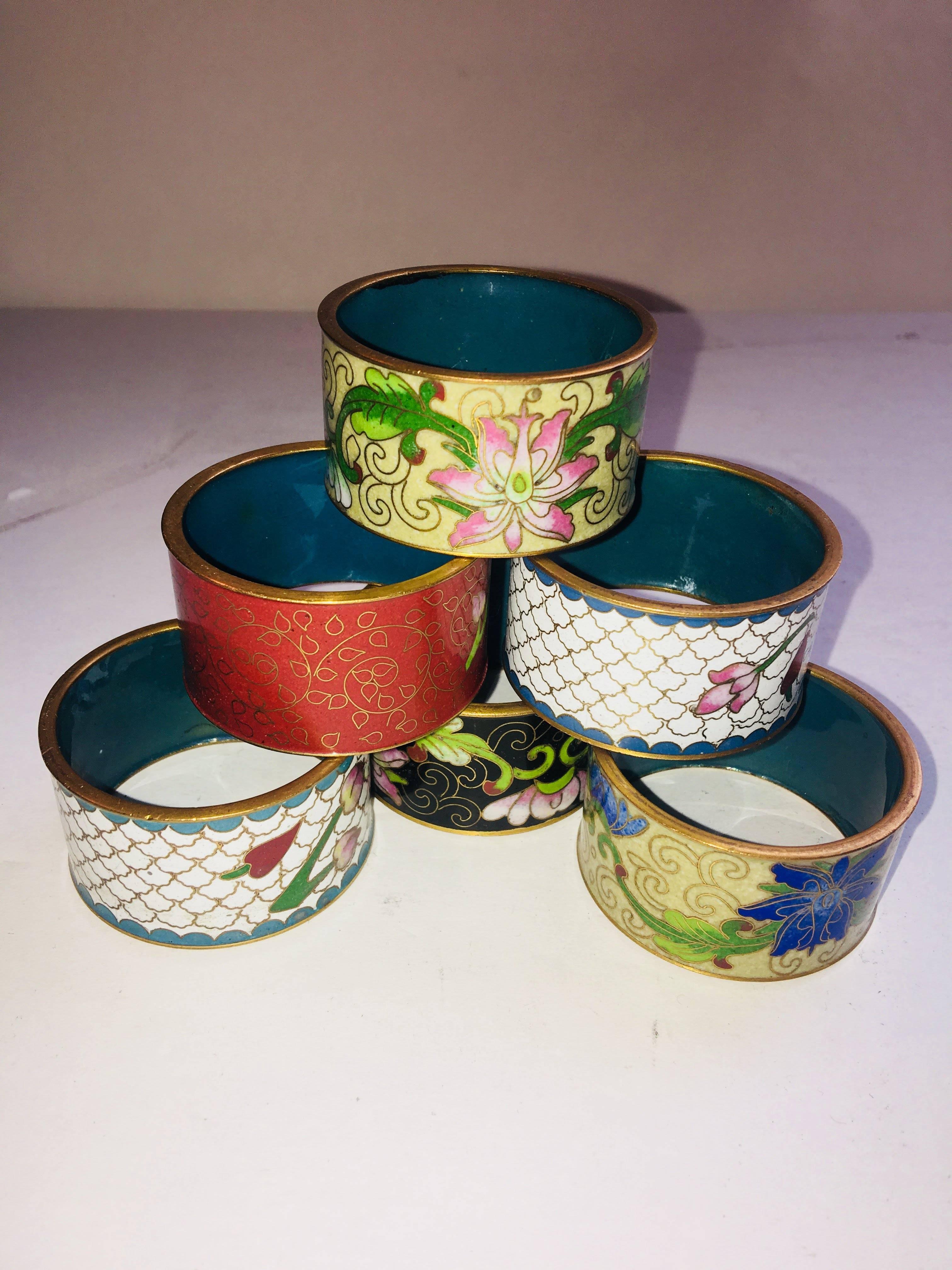 Set of six Chinese enamel napkin rings with different decorative designs on each.