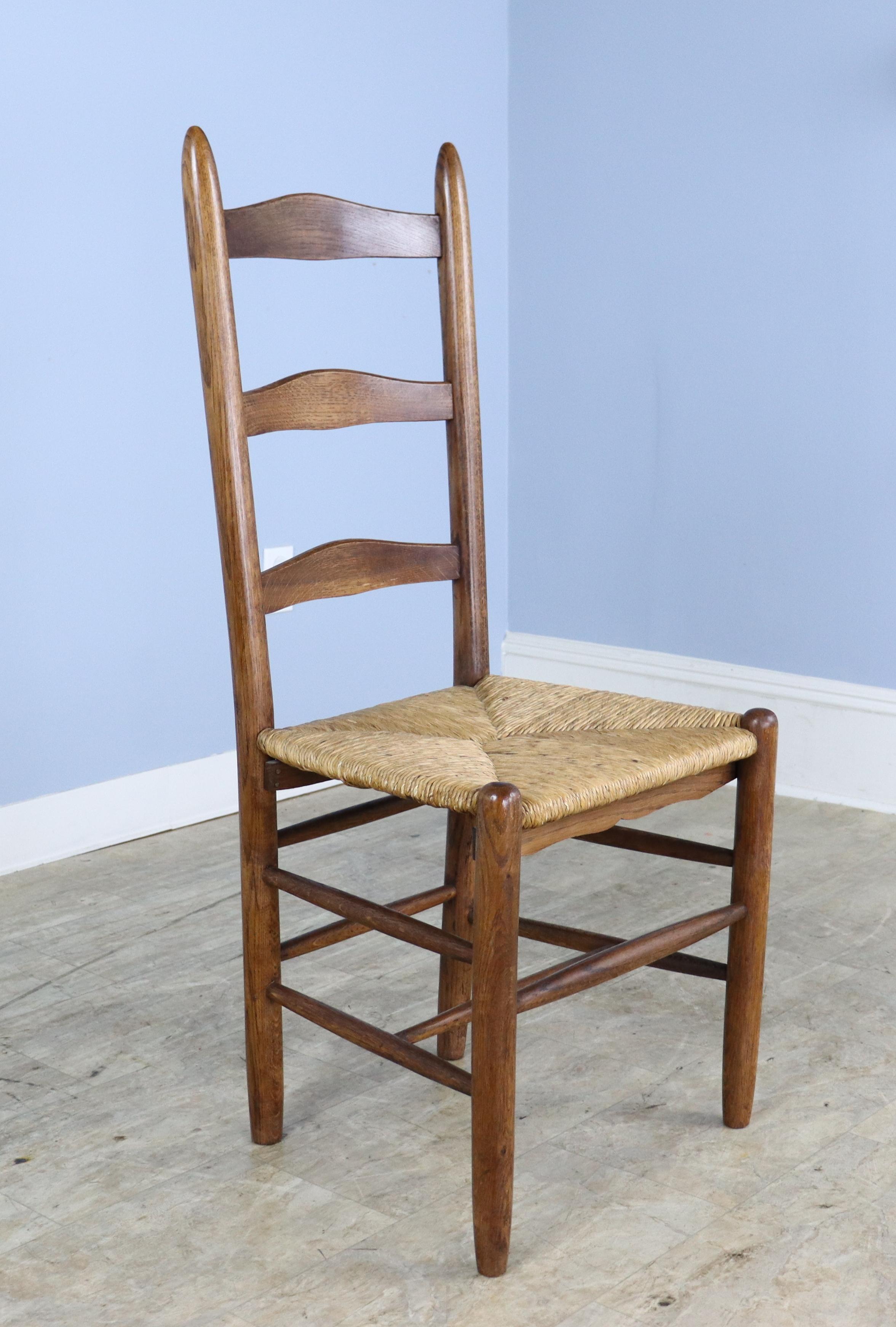 A set of 6 charming English oak ladderback chairs with their original rush seats in good condition. There is some variation in the wood color and grain, as seen in the silhouette. Although the backs of the chairs are high, the have a slight recline