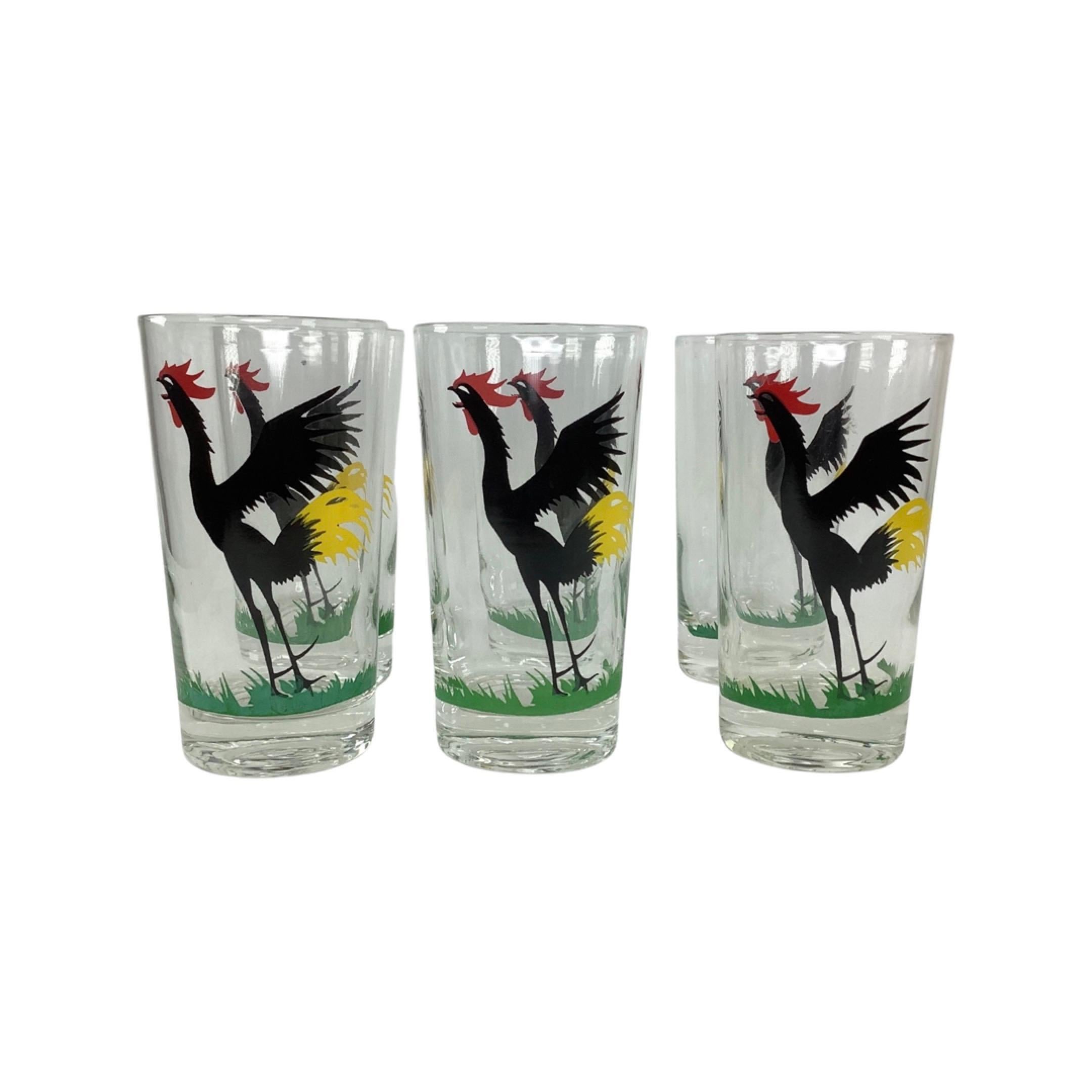 Set Of 6 Crowing Rooster Highball Cocktail Glasses. Each glass decorated with a large black crowing rooster with red combs and yellow tail feather standing in green vegetation.
