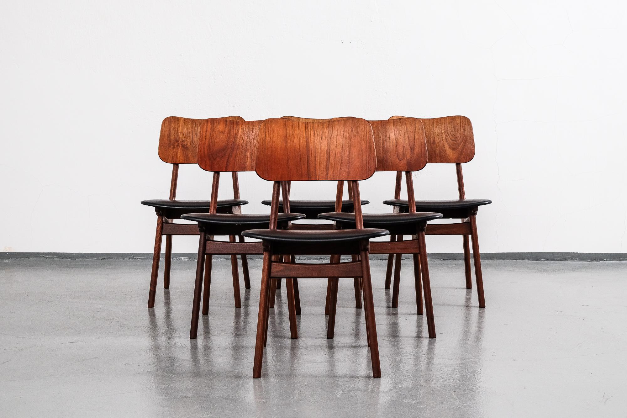 Set of six 1960s dining chairs, made by Boltinge Stolefabrik in Denmark. Solid teak frame with a bentwood teak backrest and a shaped teak handle on the back with beautiful brass details. Seats upholstered in black leatherette.