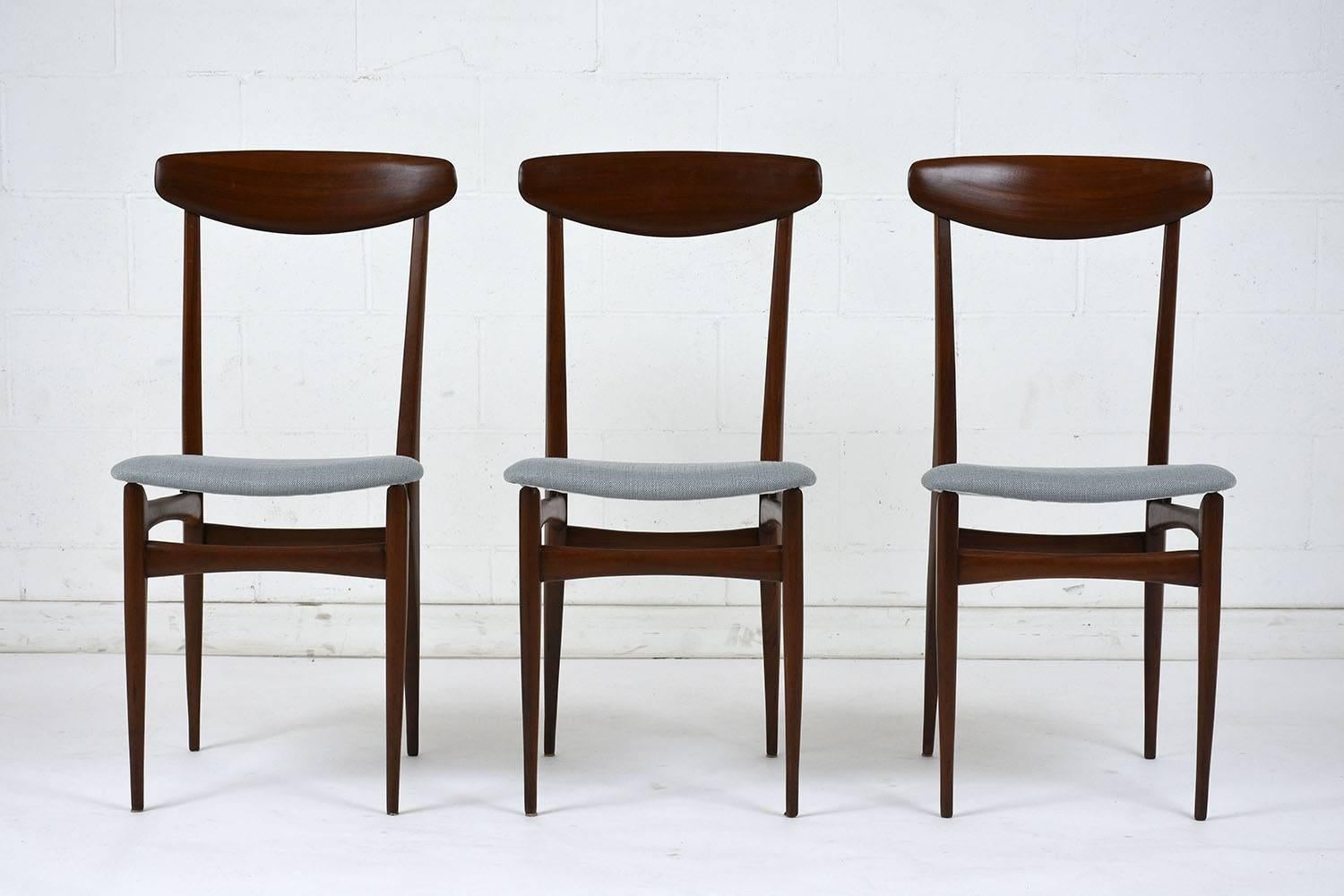 This set of six 1960s Danish Mid-Century Modern style teak wood dining chairs are stained a deep walnut with a polished finish. The sleek frames have a curved top rail and tapered legs. The seats have recently been professionally upholstered in a