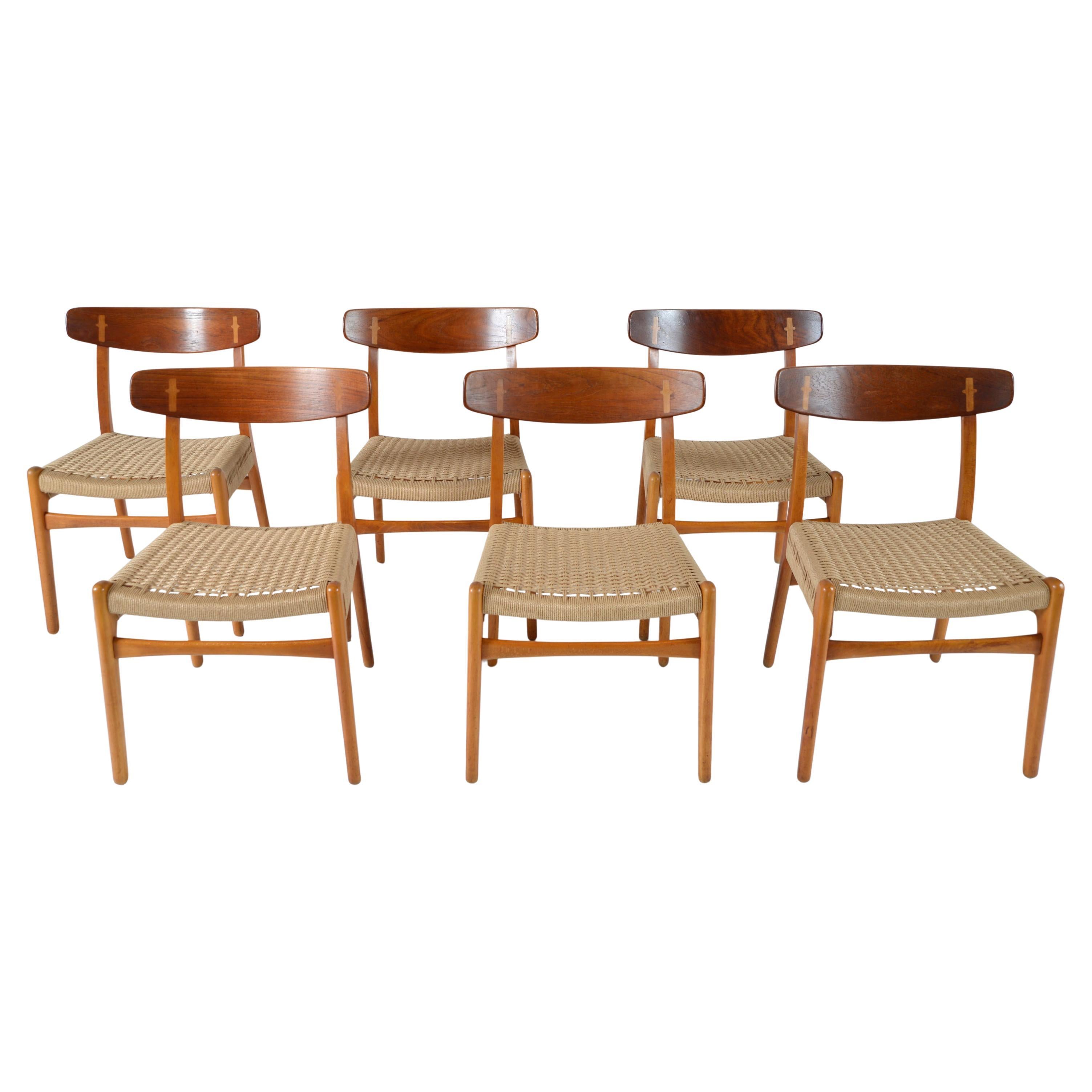 Una splendida serie di sei sedie da pranzo moderne danesi di prima generazione in Beeche con schienale in teak a contrasto. Il modello CH-23 è stato progettato nel 1950 da Hans Wegner esclusivamente per Carl Hansen & Søn, in Danimarca. I telai sono