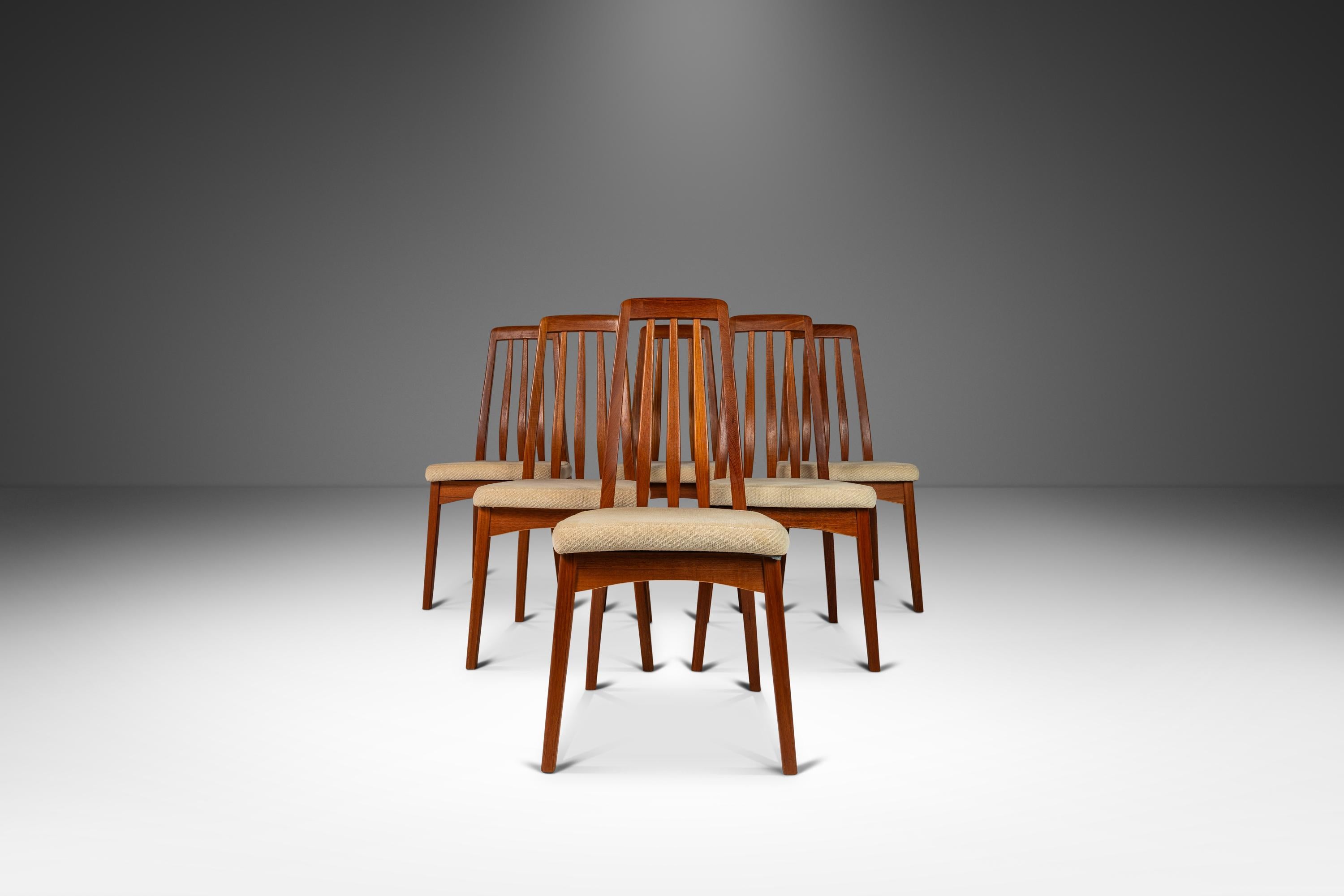 Introducing an expansive set of six beautifully sculpted Danish Modern teak dining chairs designed by Benny Linden for Benny Linden Design. These superbly crafted and sculpted modern teak dining chairs with curved backrests feature the original