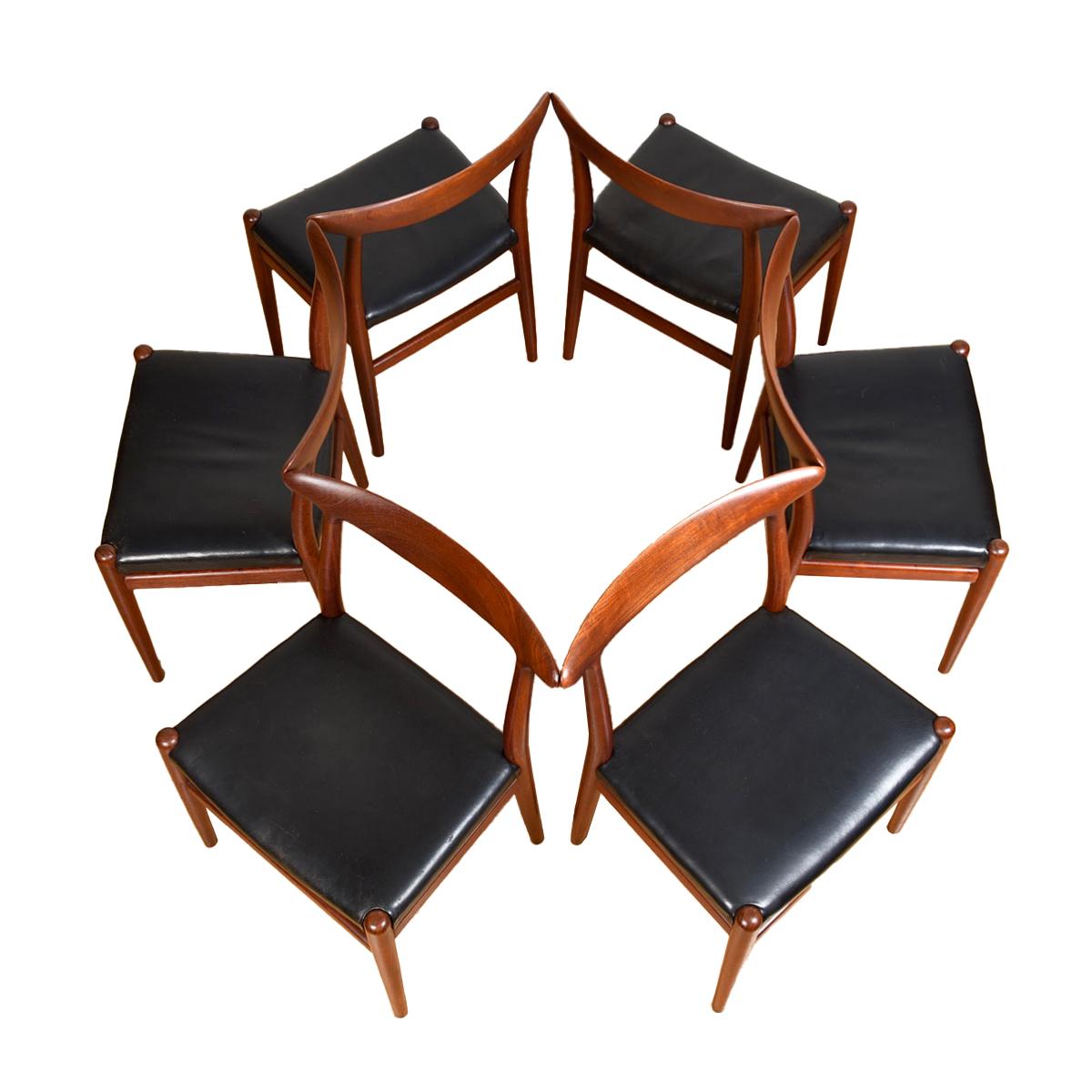 Massive Rückenlehnen aus Teakholz prägen diese Stühle, die sich in einem ausgezeichneten Vintage-Zustand befinden.
Original schwarzes Leder, das genau richtig eingefahren ist, um perfekt mit der tiefdunklen Patina des Teakholzes zu