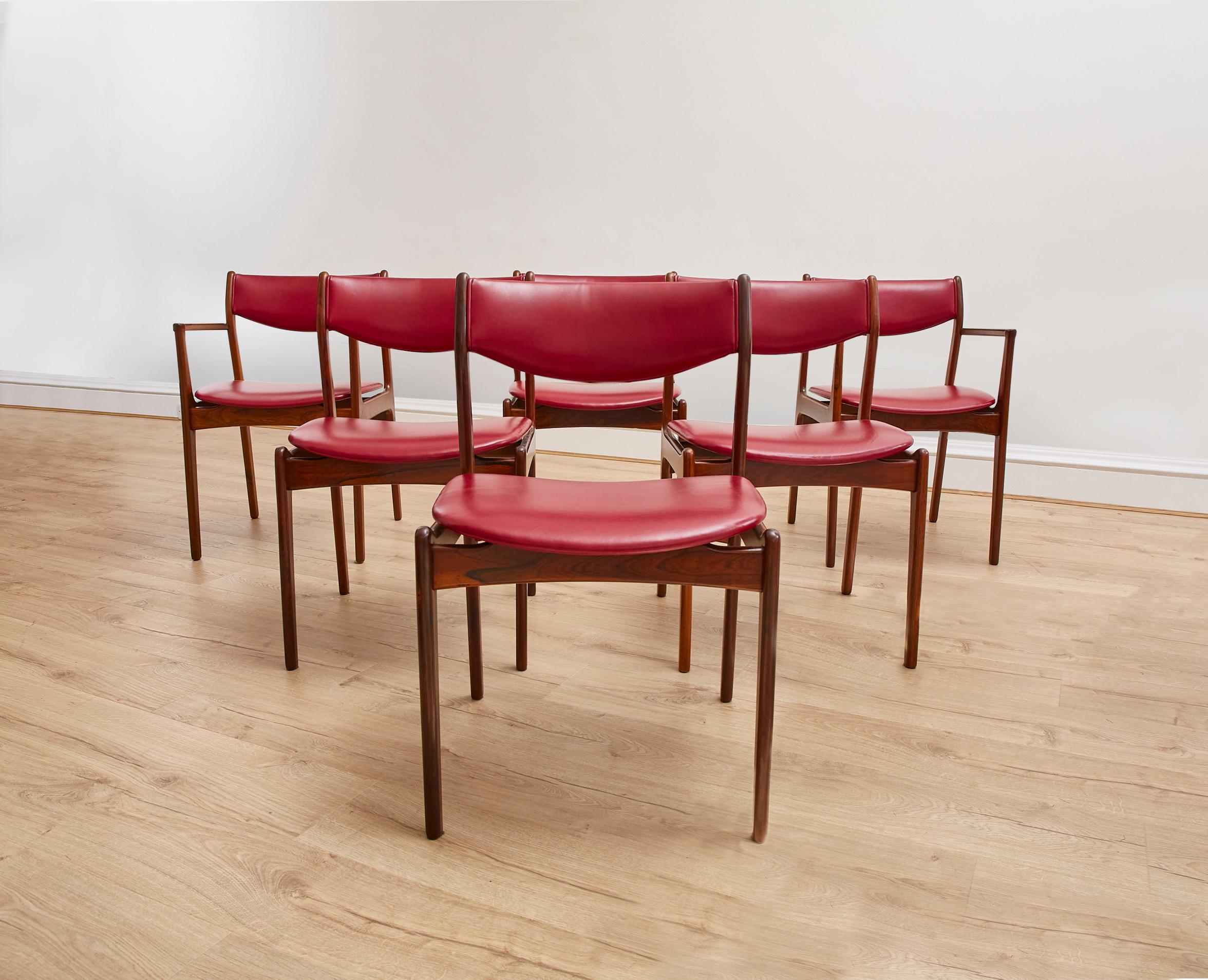 Cet ensemble de 6 chaises de salle à manger des années 1960 (4 chaises, 2 carvers) est en superbe état. Le revêtement en cuir bordeaux et la finition en bois de rose foncé confèrent un aspect sophistiqué à la salle à manger.