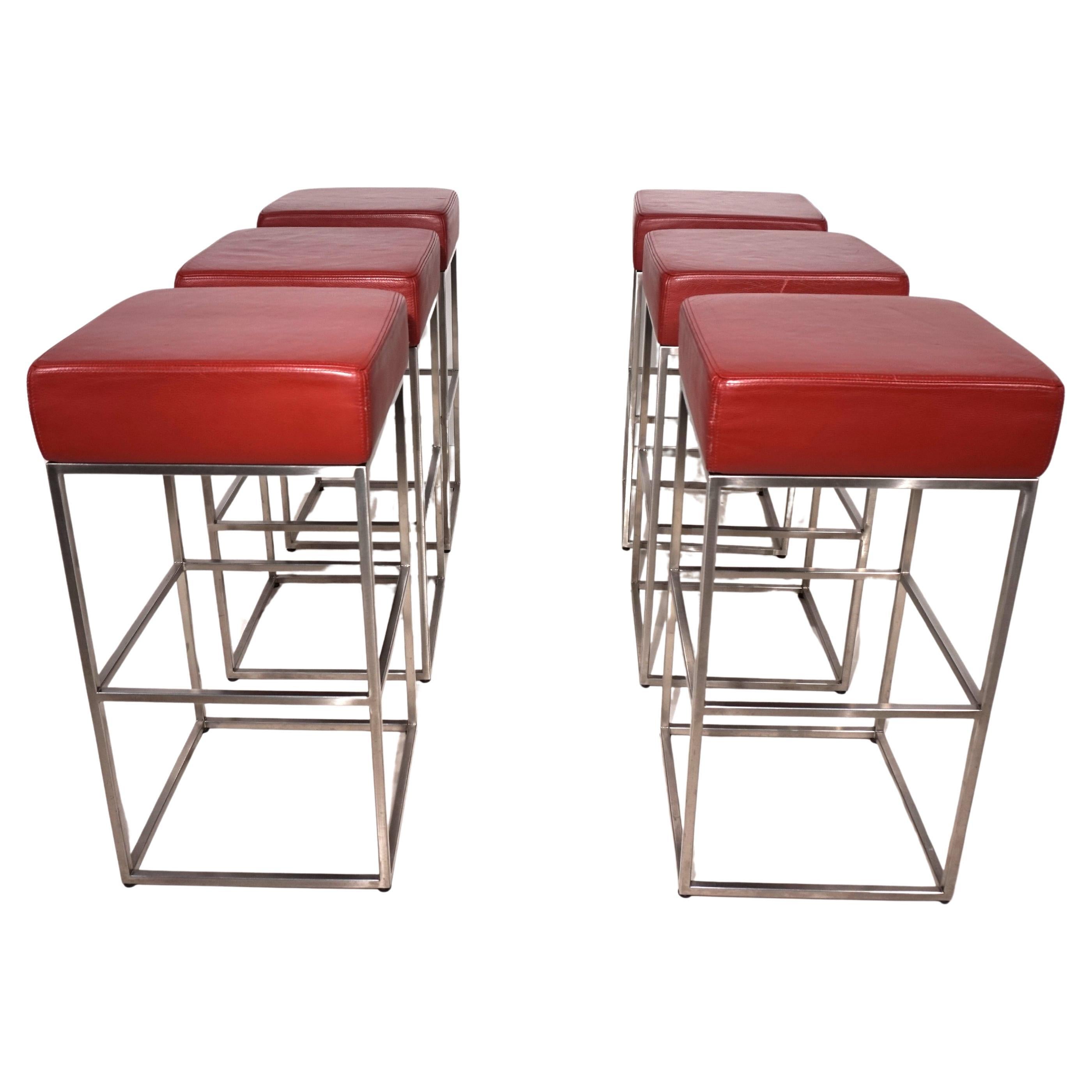 This set of six bar stools with red seats made of high-quality nappa leather is in excellent condition. The leather seats show minimal signs of wear. The cubic frames made of polished stainless steel appear almost new. The stools are available as a