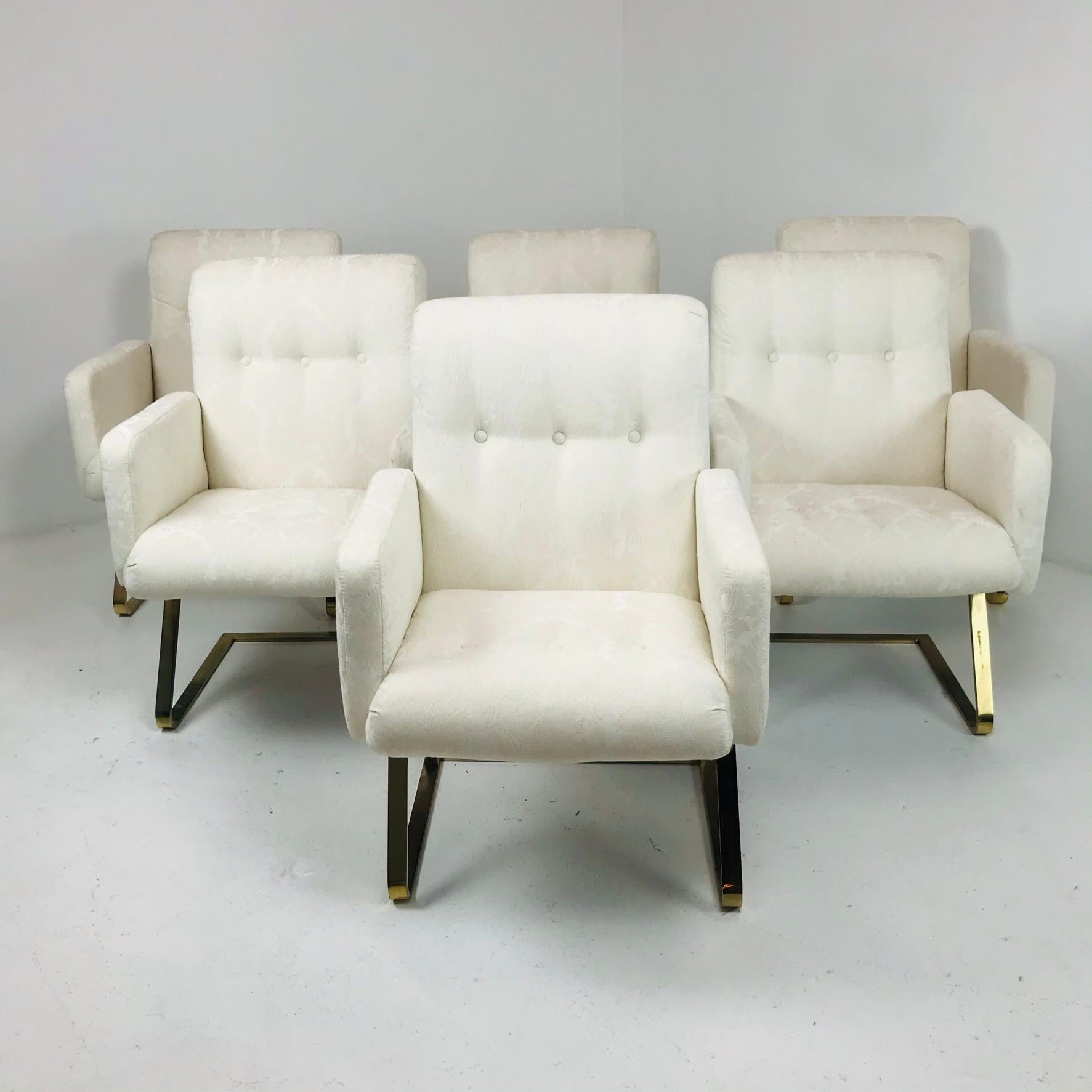 Set of 6 DIA brass cantilever dining chairs with off-white patterned upholstery.