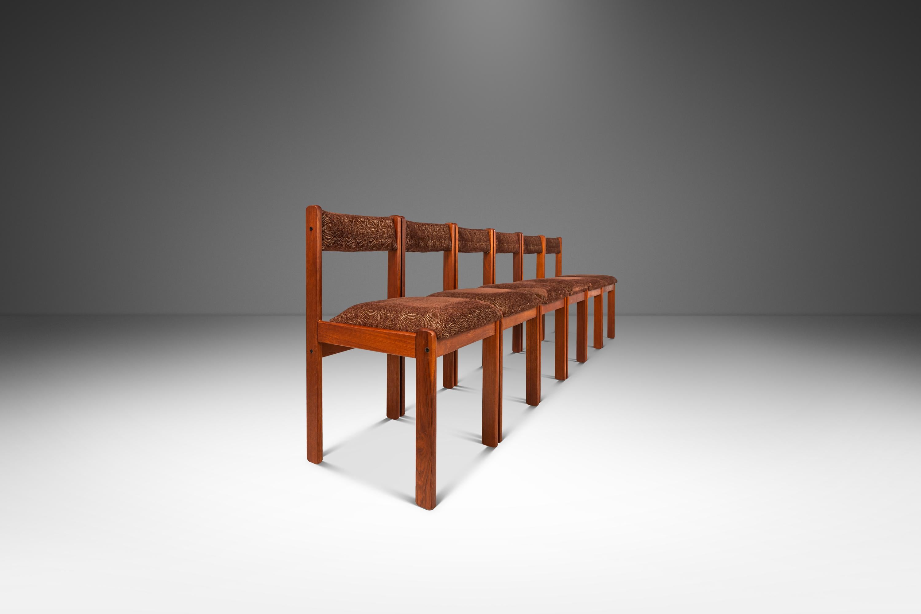Cet élégant ensemble de six chaises de salle à manger de By Design/One illustre la sophistication discrète du design moderne danois des années 1970. Fabriqués en teck massif, les cadres mettent en valeur le grain chaud et riche du bois et sa