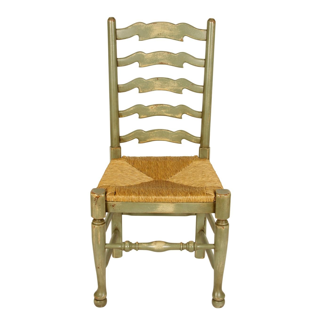 A set of ladder-back dining chairs painted in a washed celadon green with rush seats and turned legs.