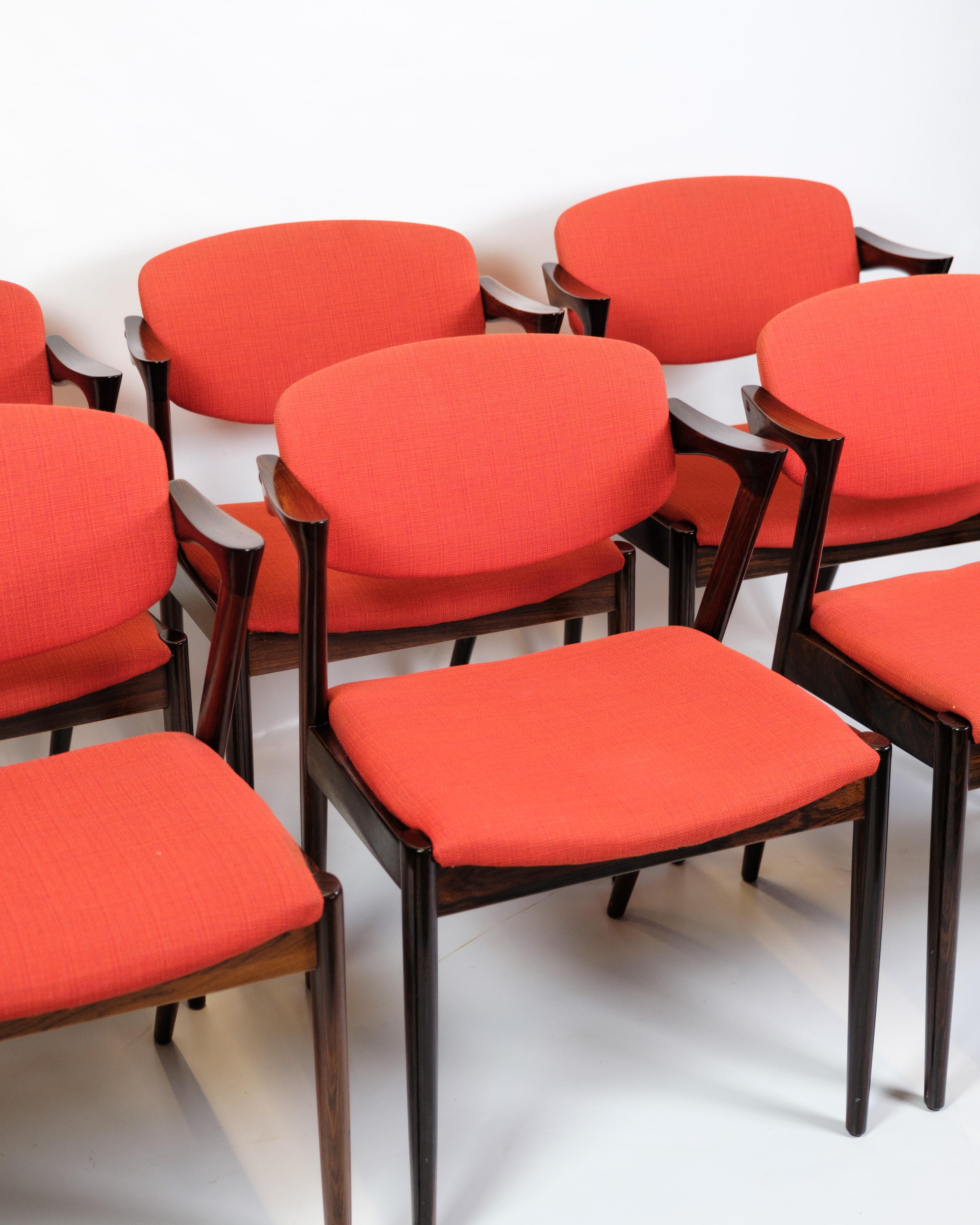 Set di 6 sedie da tavolo, modello 42, in legno di palissandro, disegnate da Kai Kristiansen e prodotte da Schou Andersen negli anni Sessanta. Le sedie sono dotate di cuscini in tessuto rosso che aggiungono comfort e un bel contrasto con il tono