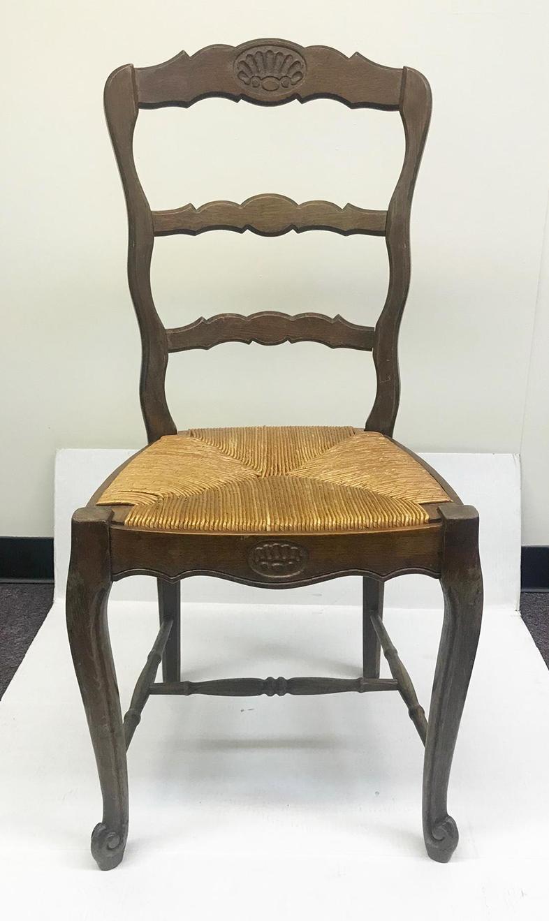 Set of 6 vintage French side chairs. Solid oak with a hand done rush seat. Simple shell motif carved on the inside back and a graceful leg. These chairs are from the Brittany region of France and are a traditional design for this region of France.