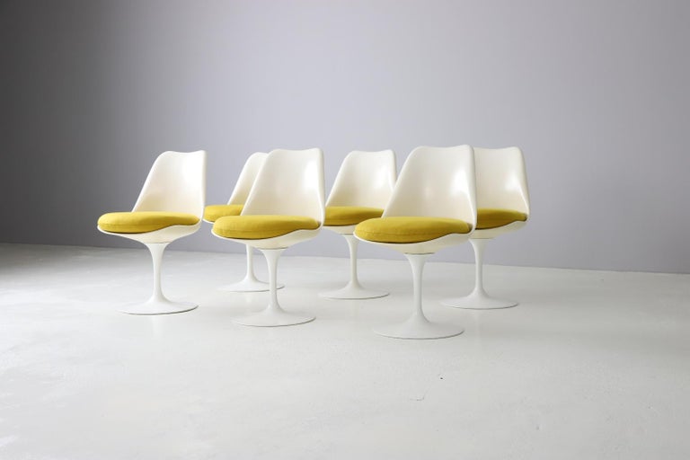 Iconic set of 6 Tulip chairs designed by Eero Saarinen and produced by Knoll in the early 1960s. These chairs are early editions with swivel function. 
Aluminum base with a fiberglass shell, both covered in white rislan. New foam and reupholstered