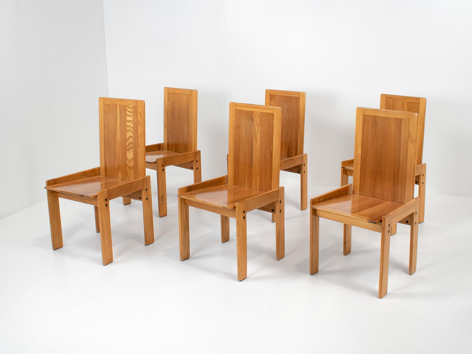A set of 6 chairs in pale elm wood. It perfectly matches any kind of natural-style table, such as travertine or wood. 
It creates the perfect wabi-sabi style due to its imperfections and naive design.

The design of the chairs is very