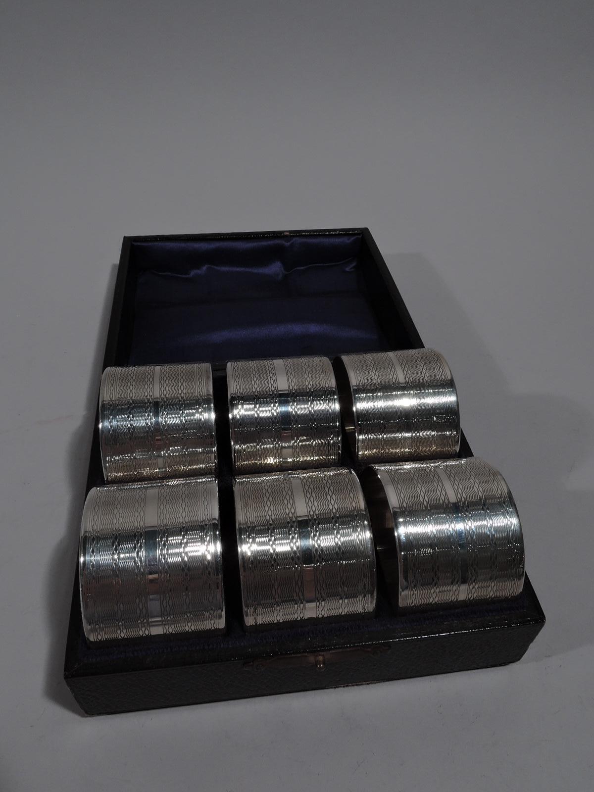 Set of 6 George V sterling silver napkin rings. Made by Ebenezer Newman in London in 1913. Each: Engine turned wave ornament and heraldic cartouche (vacant). Snazzy prewar Art Deco. In leather-bound case with silk lining and fitted velvet. Fully