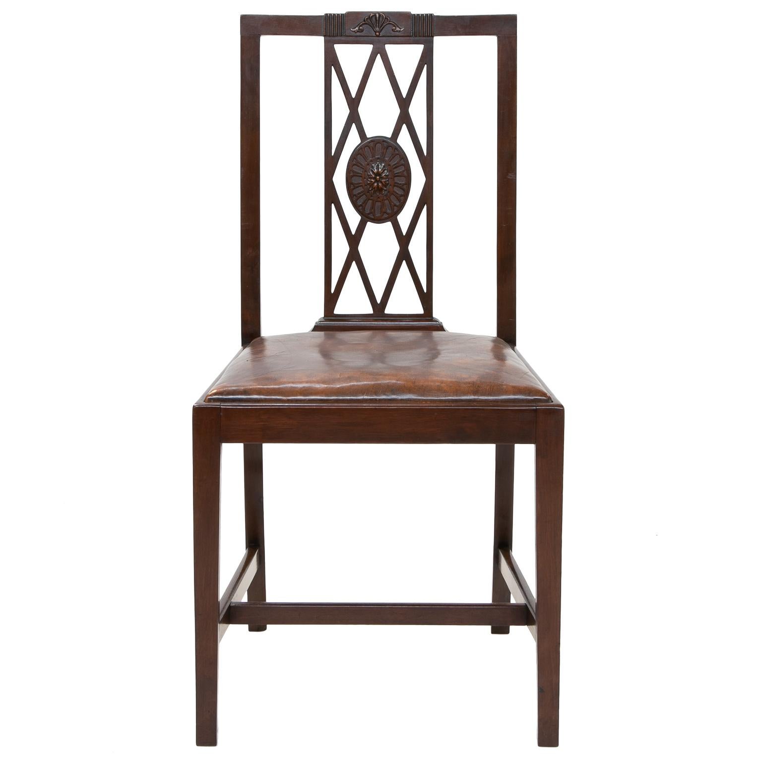 Set of 6 English mahogany side chairs
Set of 6 English mahogany side chairs with leather seats, H-stretcher, straight legs, and rectangular backs with pierced diamond shapes, center medallion and carved crest on the chair, circa 1930s.