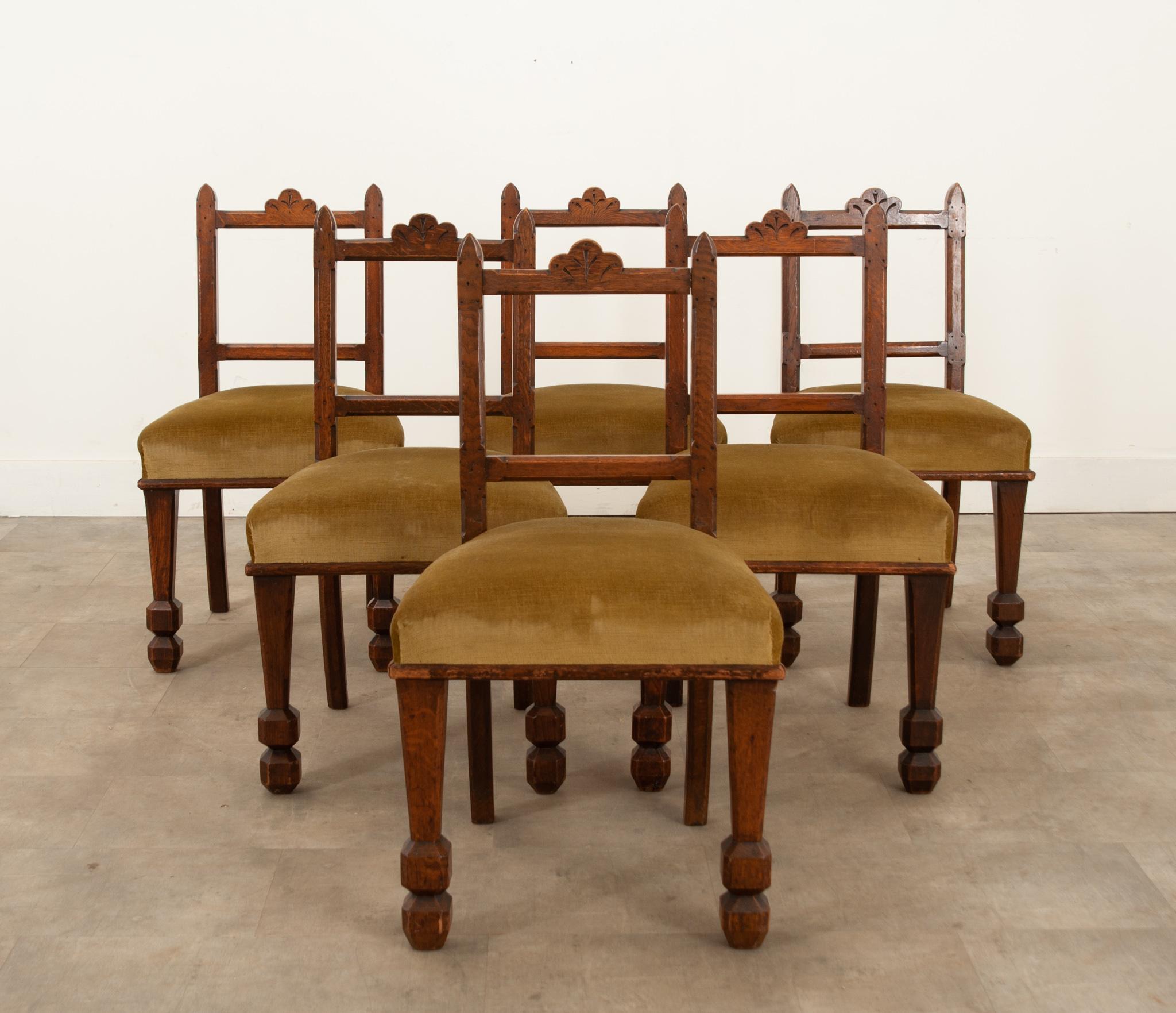 Set of six Edwardian period carved oak dining chairs dating to circa 1890 with green velvet upholstered seats. They have stable, oak frames which have a beautiful time worn patina and feature nicely carved Gothic Revival style backs, and are raised