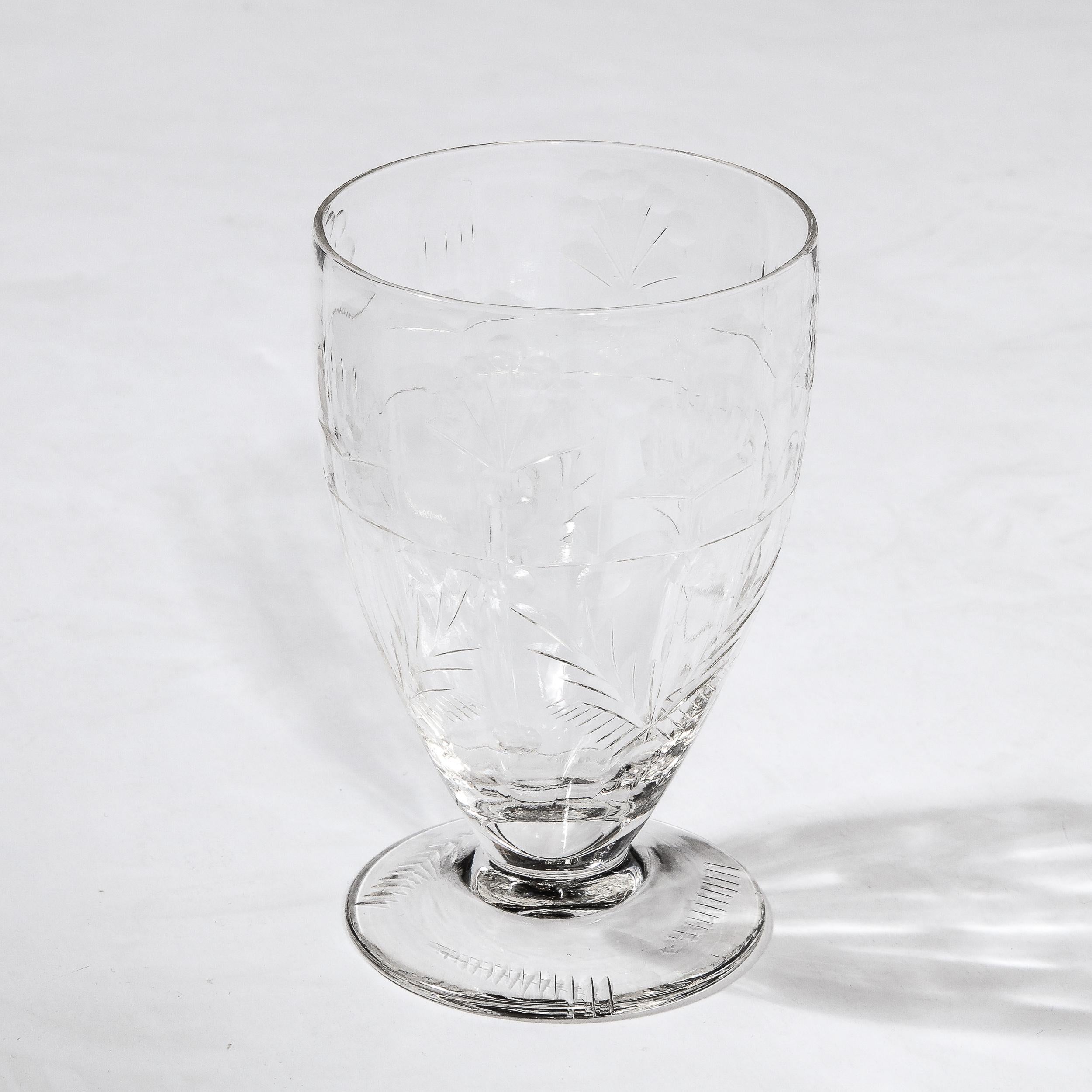 This refined set of six Art Deco crystal water glasses were realized in France circa 1925. They offer a subtly conical body sitting on a round base that protrudes beyond the perimeter of the glass. The surface offers an abundance of stylized foliate