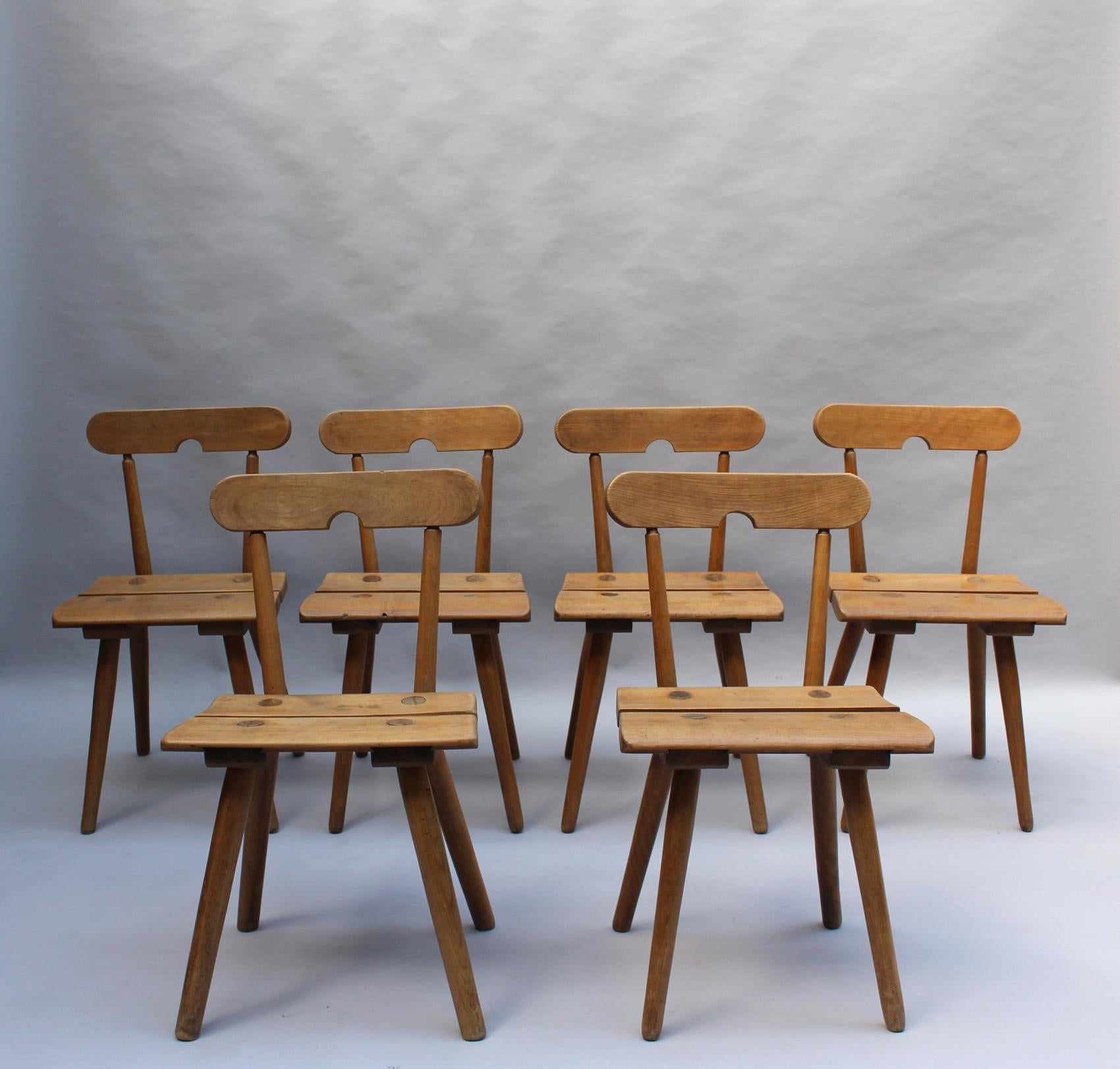 A set of six fine French midcentury solid beech side chairs with an arch-shaped cutout handle in the seat back.
 
