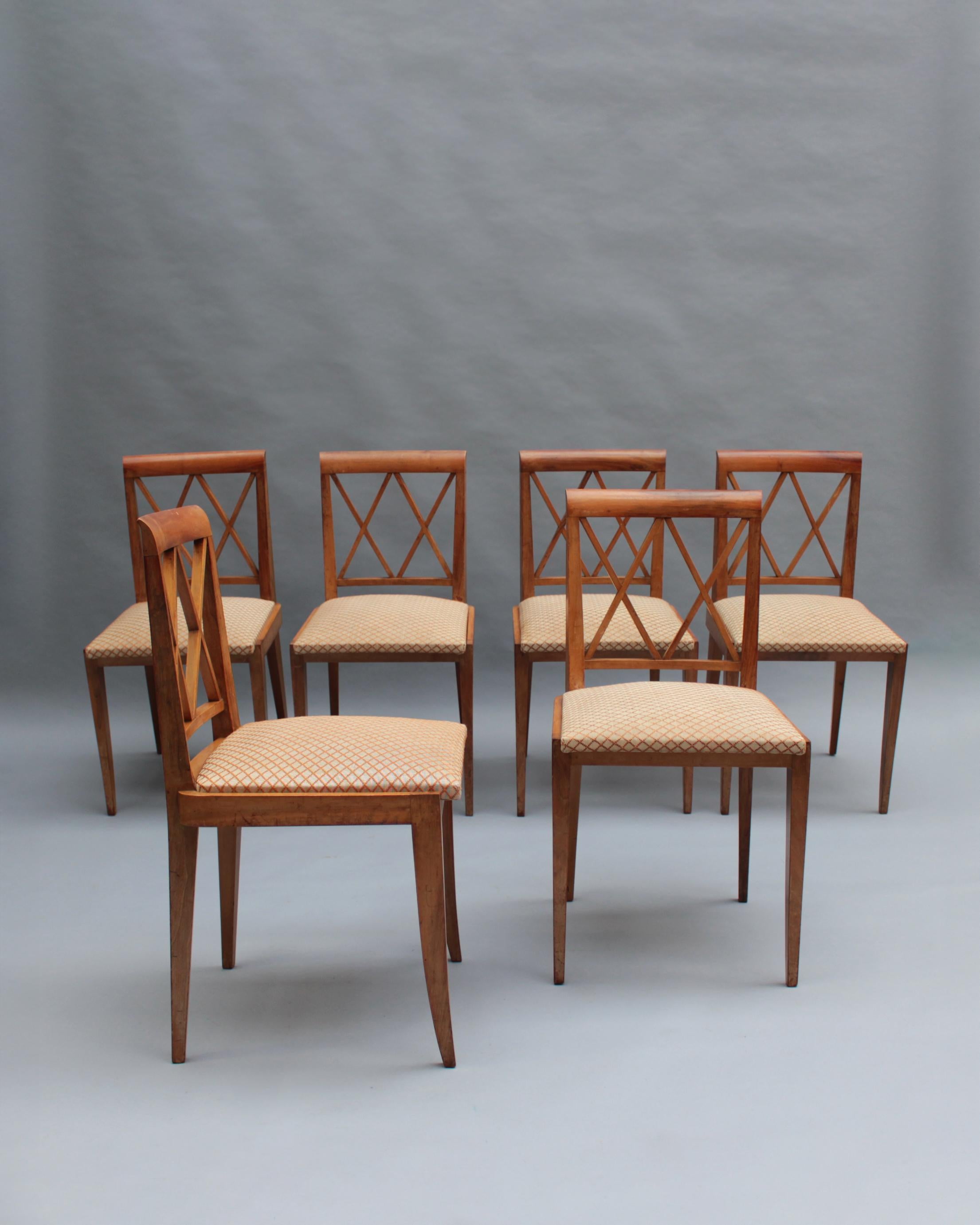 Conjunto de seis finas sillas auxiliares francesas de mediados de siglo, de nogal macizo y respaldo enrejado, a la manera de Jacques Adnet.