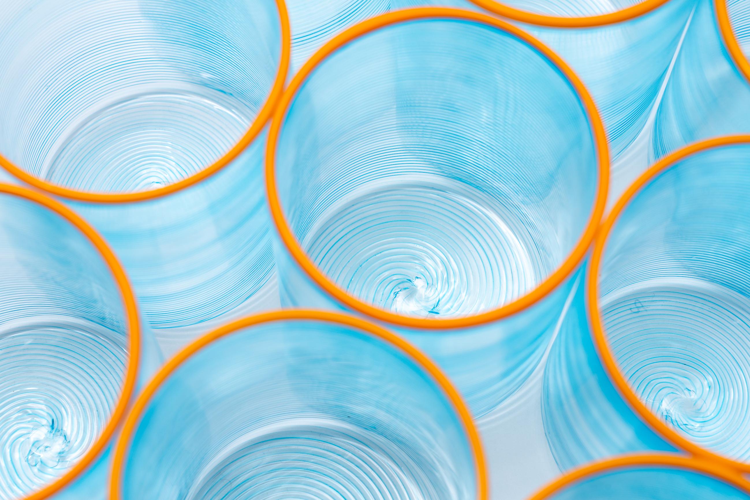 Die Fizzy-Gläser sind zylindrische Kreationen, die mit der traditionellen Rigà-menà-Technik hergestellt werden, bei der das Glas in einer einzigen Bewegung gestreift, gedreht und gezogen wird. Das Ergebnis ist ein lebendiges Streifenmuster, das in