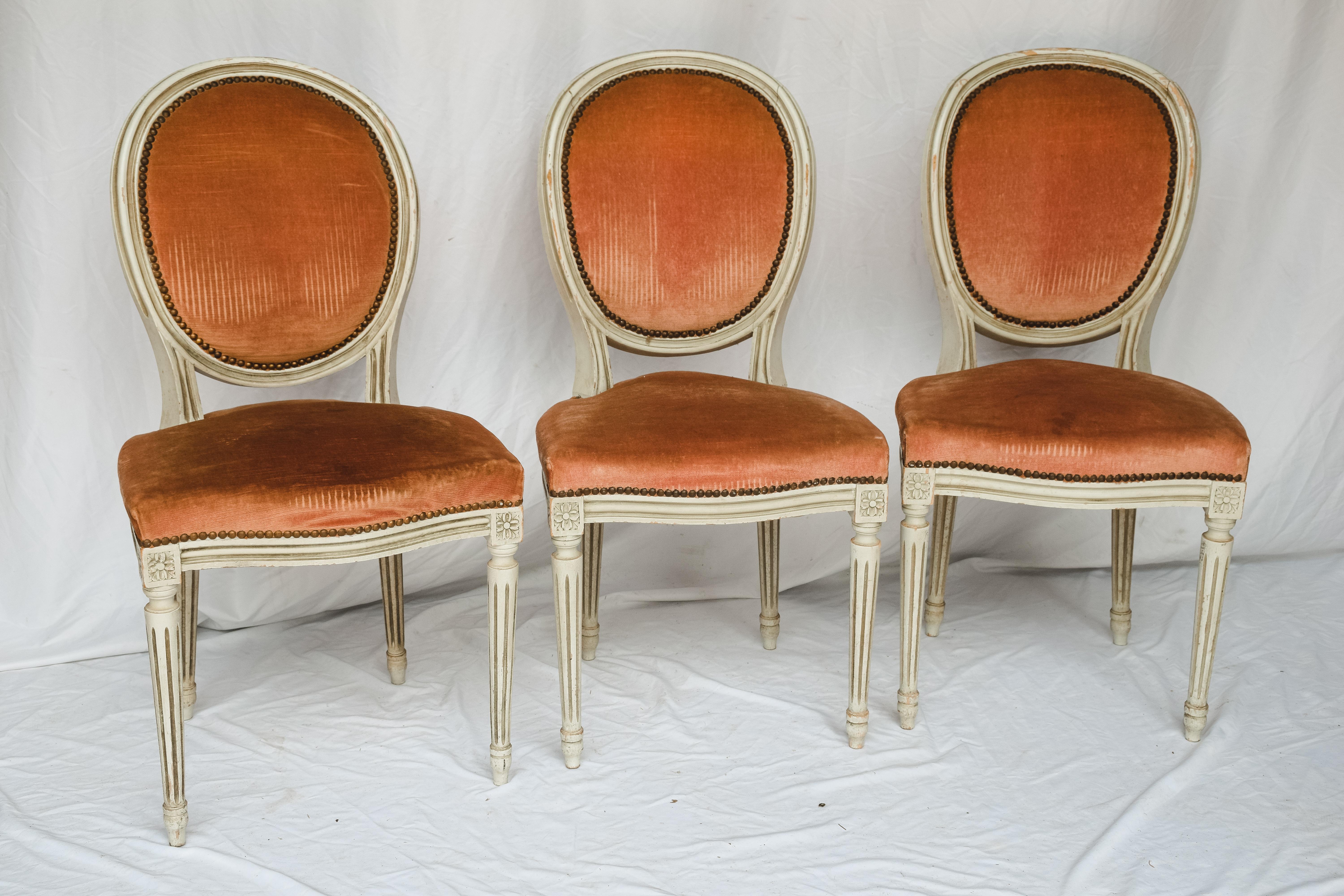 A charming Set of six Louis XVI -style painted dining room chairs- oval backs on fluted tapered legs. The set still appears to be covered in their original mohair fabric, although it definitely has seen better days. The padding on the chairs also