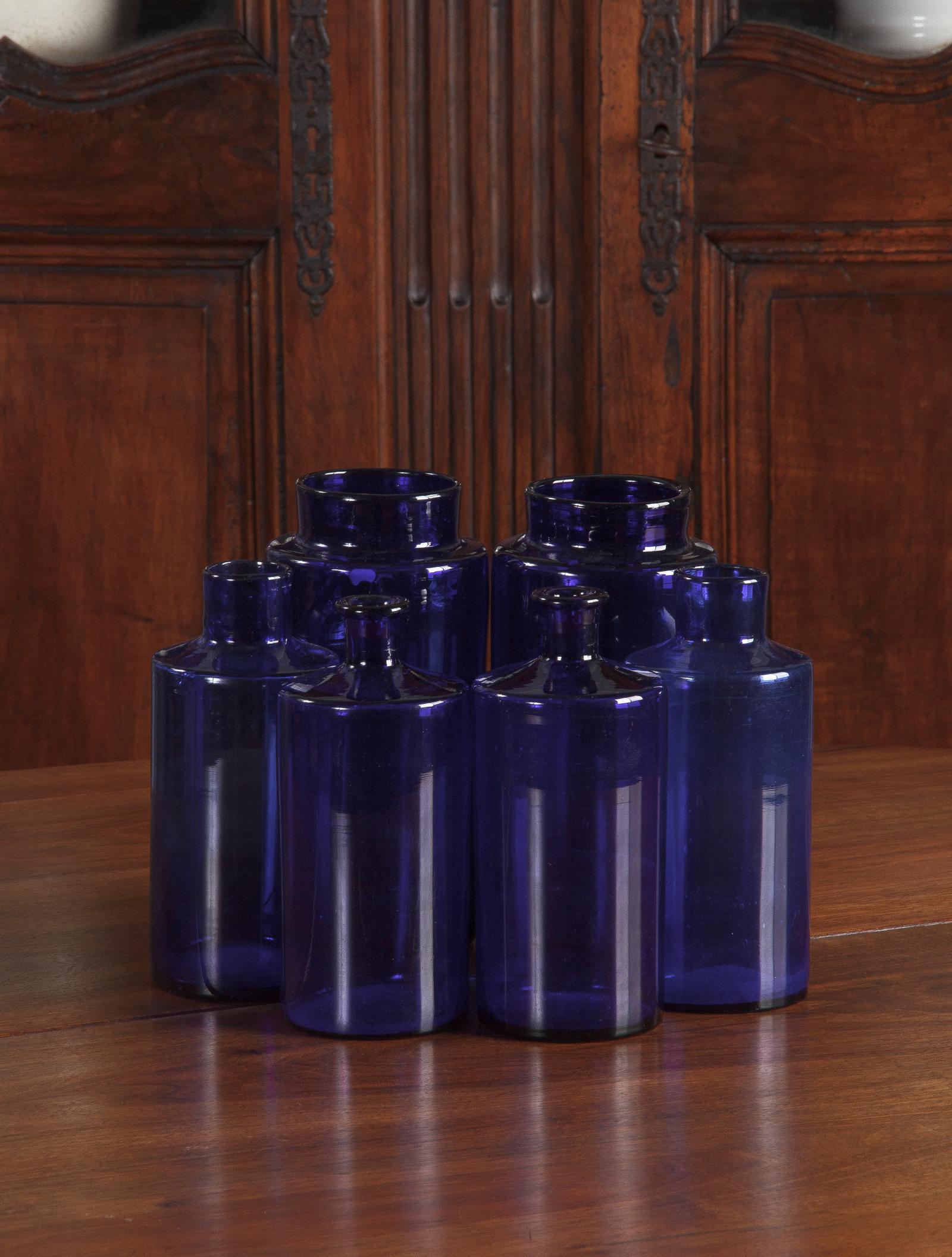 A set of 6 striking French hand blown cobalt blue glass pharmacy bottles, circa 1930s. Bottles have straight sides and a slight slope up to the necks. The two largest bottles feature a short neck and a wide mouth, they measure 9.5