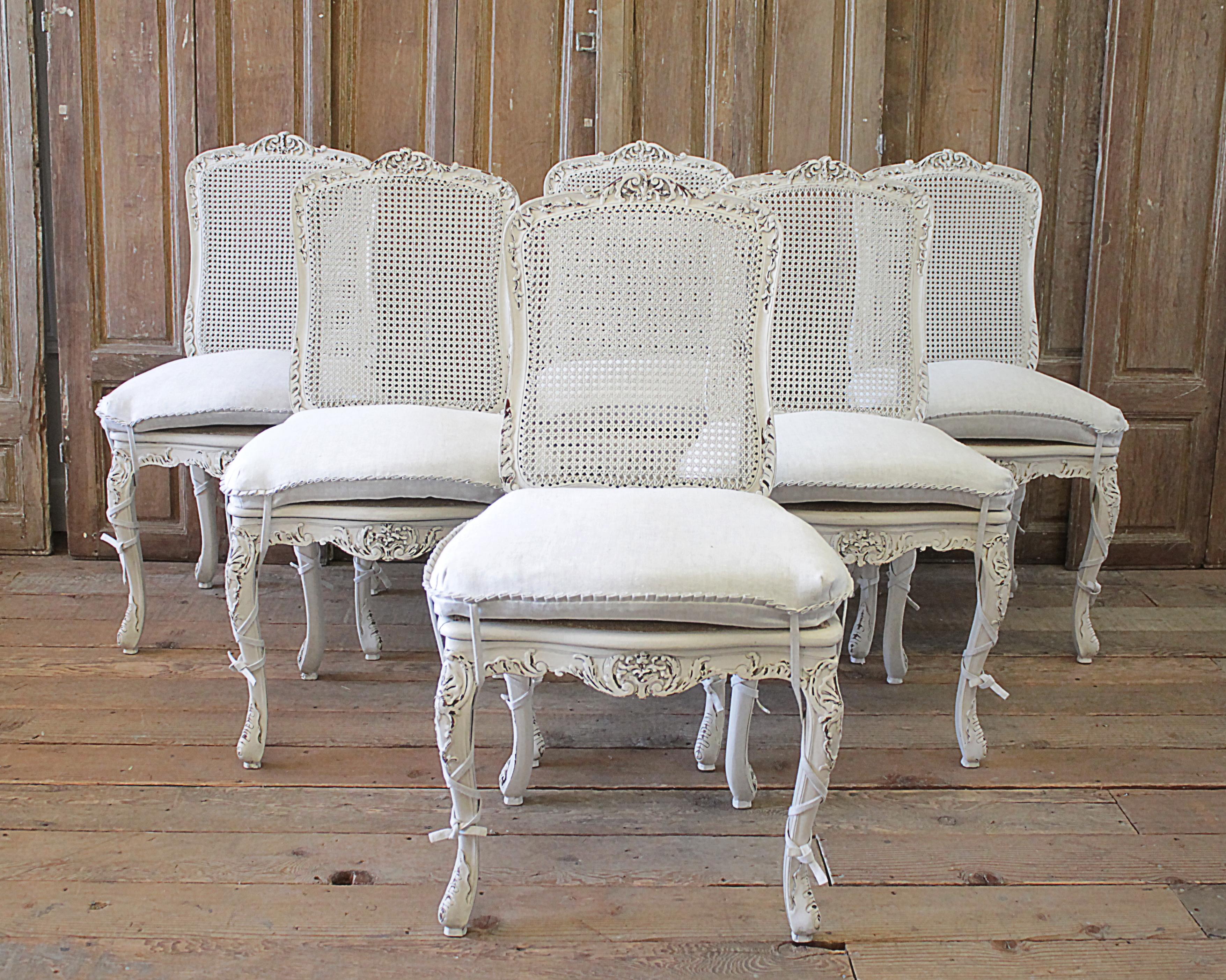 Set of 4 French country painted cane back dining chairs.
Painted in our oyster white finish, with subtle distressed edges, and finished with an antique patina. We customized these with a linen cushion with ruffle edges, and ballet tie legs. 100%