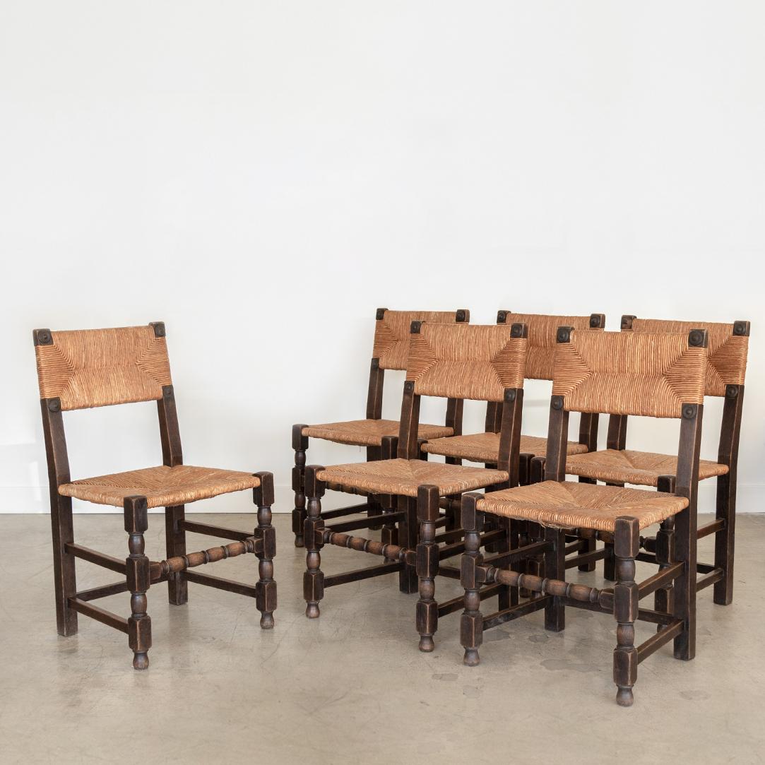 Great set of 6 French wood and woven dining chairs in the style of Charles Dudouyt from the 1940's. Dark wood frame with beautiful carved wood detailing. Original woven seats show nice age and patina.