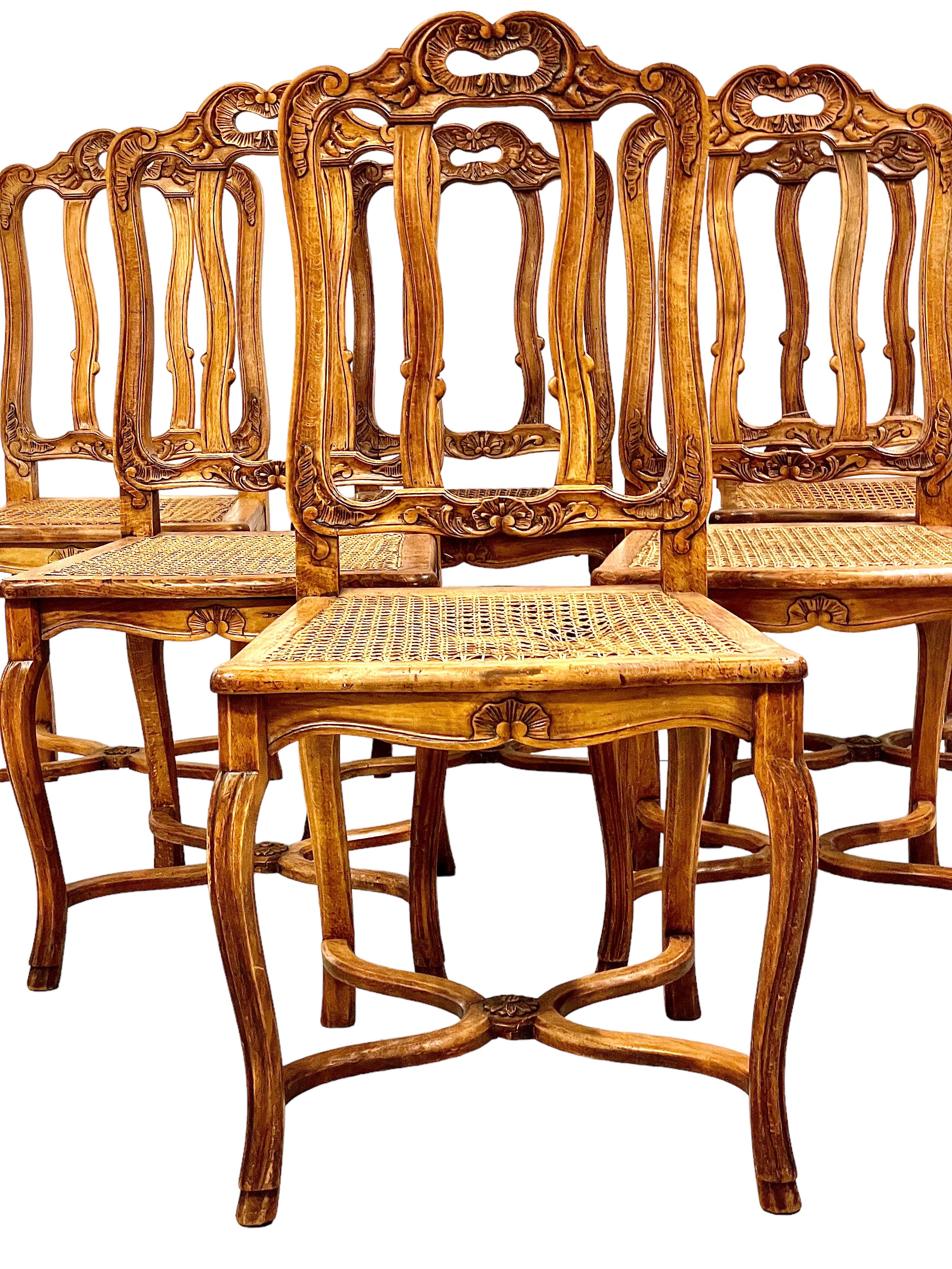This exquisite suite of six Louis XV-style dining room chairs features a stunning display of elegant craftsmanship and intricate carving in high-quality walnut hardwood. The delicately moulded and carved details of each chair enhance the overall