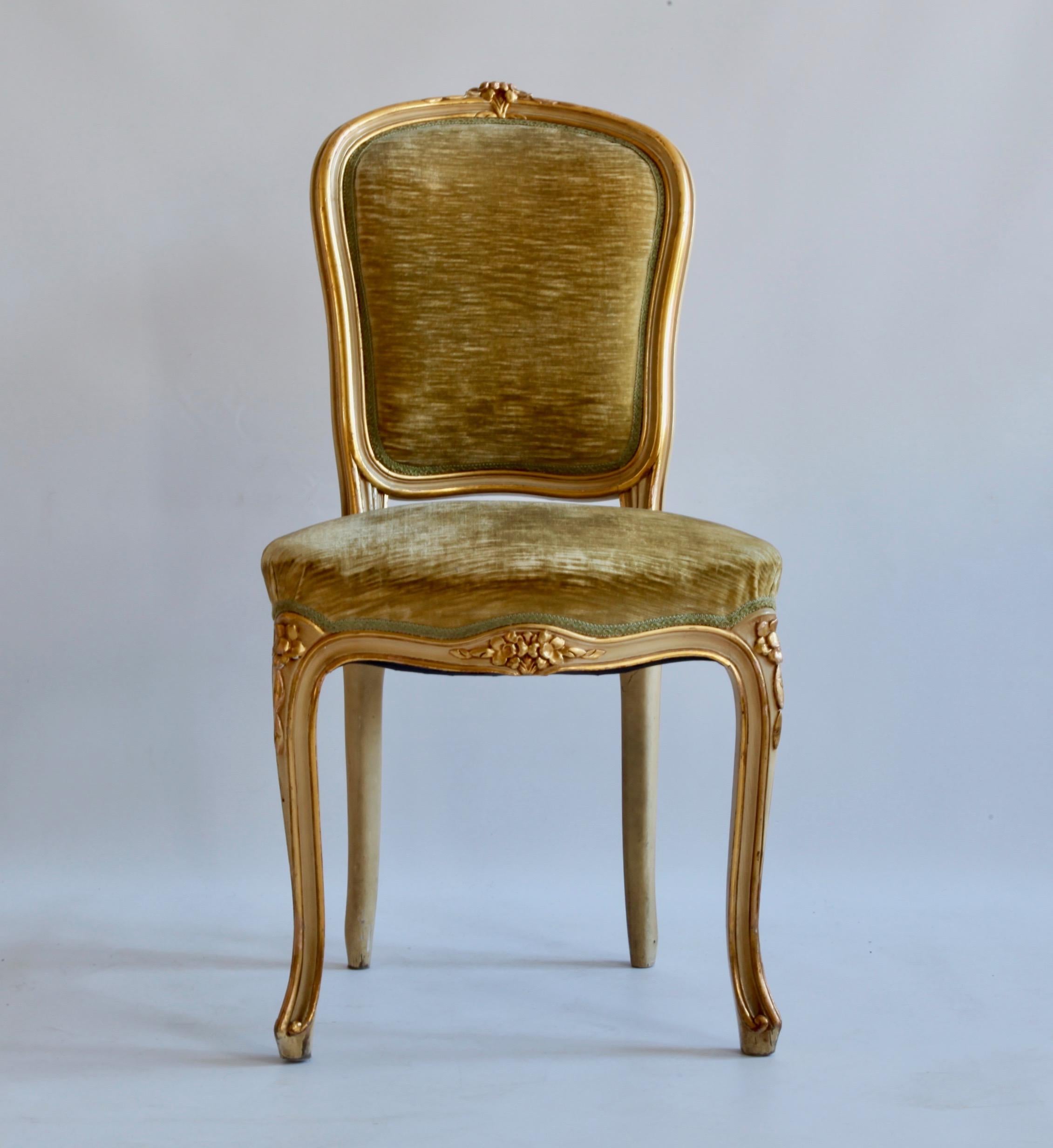 A complete set of 6 dining chairs hand carved in solid wood in the Louis XV style, designed with beveled outlines and floral detailing displayed on the top, legs and front of the seat. The chairs have an original cream white paint finish, naturally