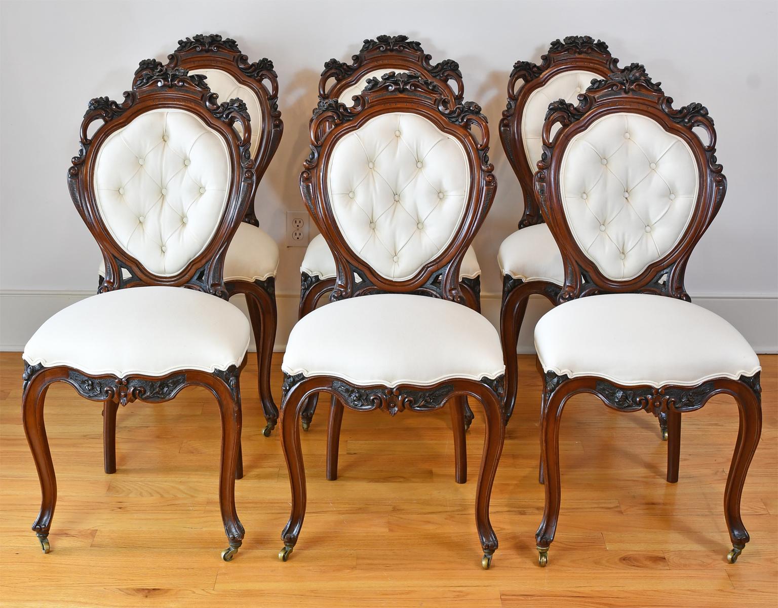 A set of 6 finely-carved Napoleon III dining chairs in a dark chocolate-colored mahogany with upholstered seat and tufted balloon-back. Carved embellishments on chair frame include pierced scrollwork with foliate and floral carvings. The upholstered