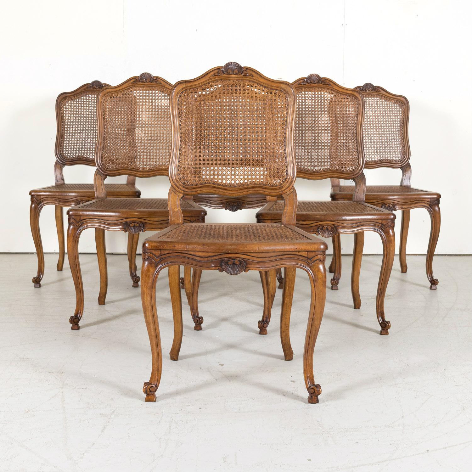 A lovely set of 6 French Country Louis XV style carved dining side chairs from Provence with hand-caned seats and backs, circa early 1900s. Featuring traditional Provençal carvings, each chair is handcrafted from solid walnut and decorated with
