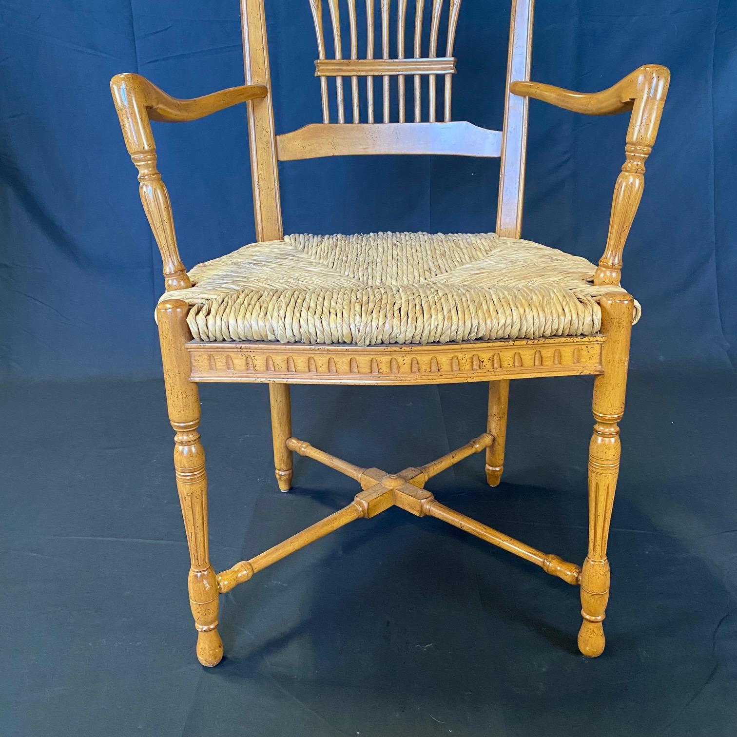 Beautiful carving on this set of 6 French provincial style rush-seated dining arm chairs having arched crest rails, finials,  wonderful spindle wheat sheaf backs and rush-woven seats on turned legs joined by 