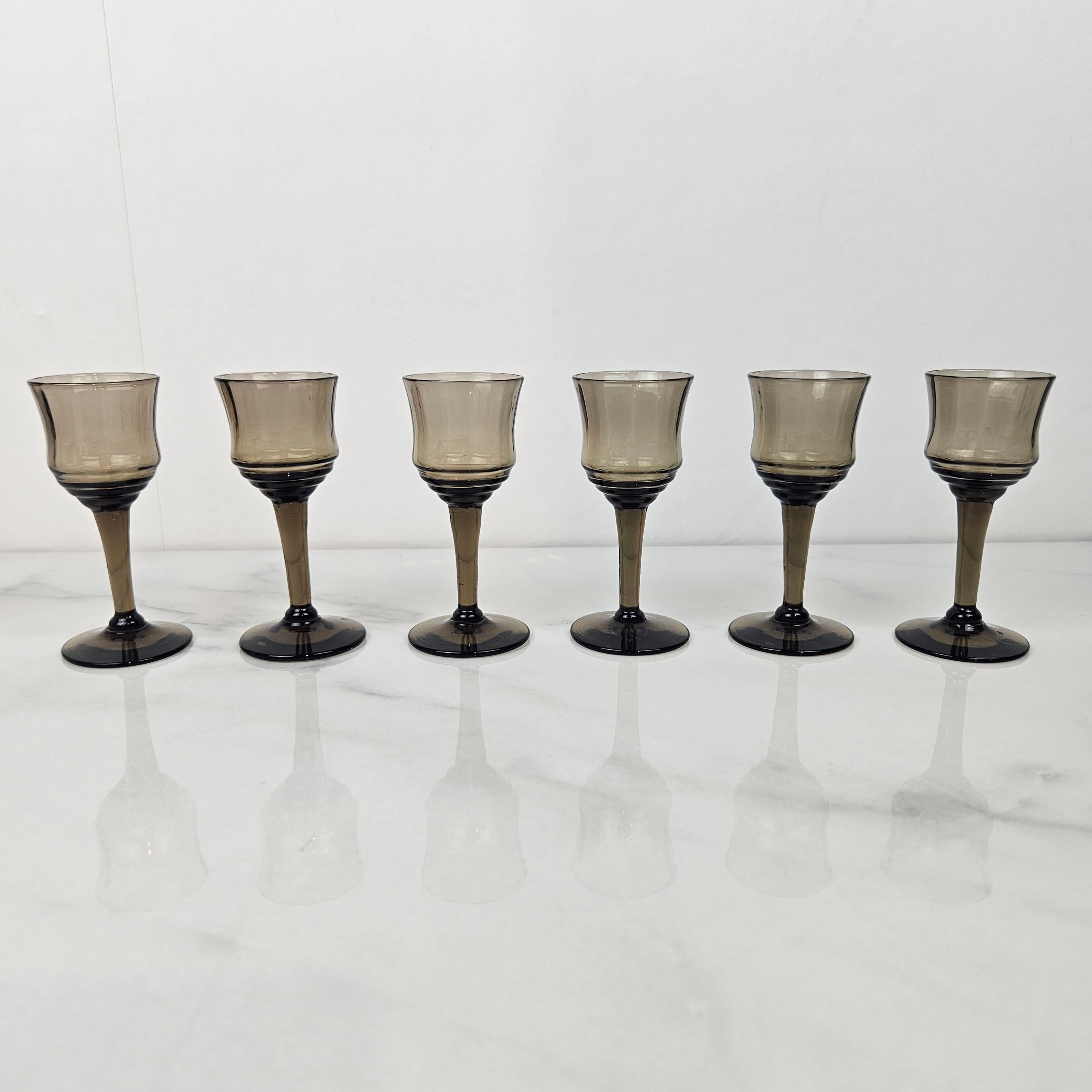 Elegant ensemble de six verres à liqueur soufflés à la main en France, datant des années 1930. 
Chaque verre présente une magnifique teinte gris fumé avec un subtil dégradé - un véritable exemple de l'artisanat français du début du 20e siècle.

Leur