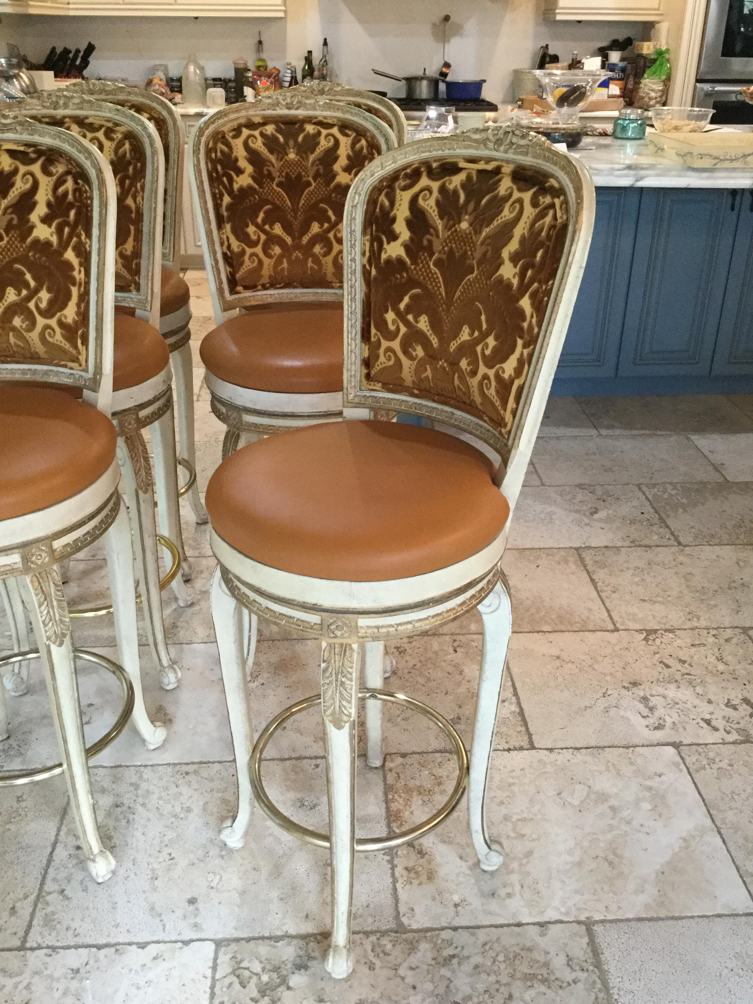 Elegant Louis XV style painted bar stools. This set of 6 swivel bar stools features a faux-leather seat and a rich velvet brocade upholstery. There are gold accents on the legs and a brass bar to place your feet for comfort. Very good condition.